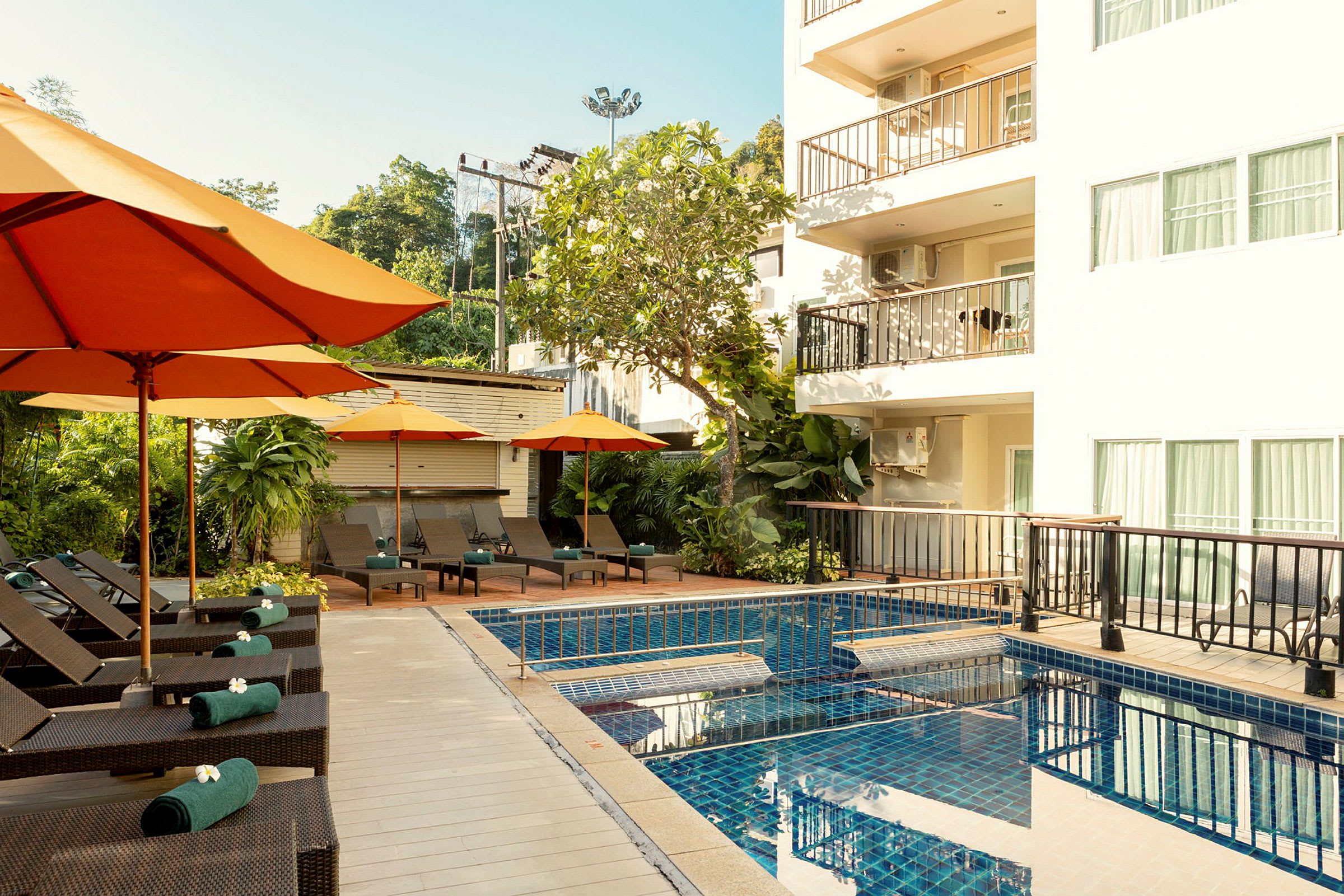 Poolområde vid ett hotell med solsängar och orange parasoller. (AI-genererad text)