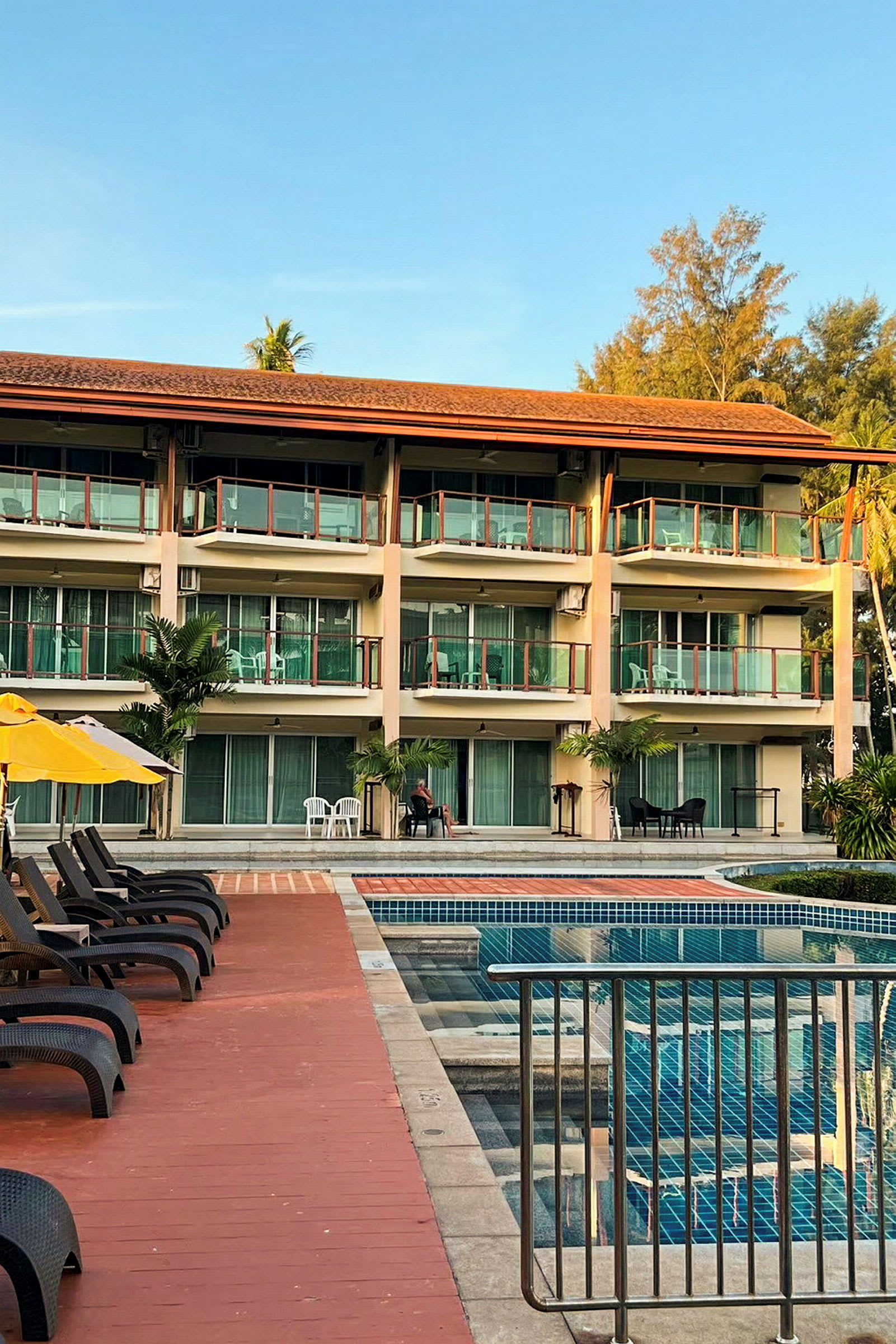 Hotellbyggnad med pool och solstolar. (AI-genererad text)