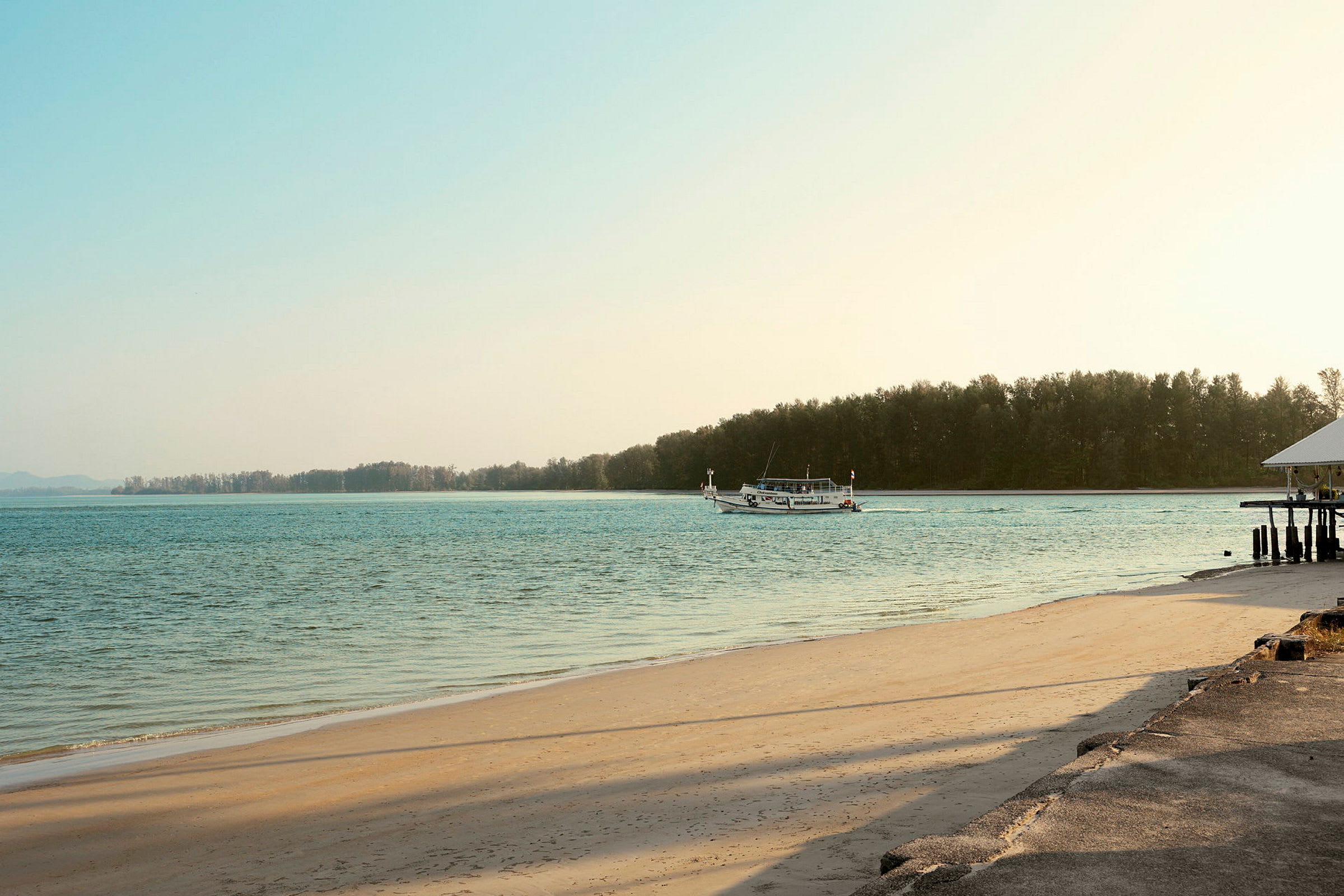 En strand med en båt på vattnet och träd i bakgrunden. (AI-genererad text)