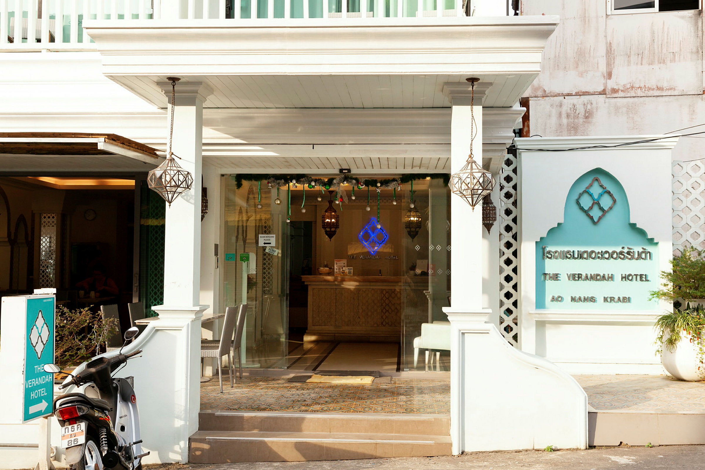 Framsidan av The Verandah Hotel med en motorcykel parkerad framför ingången. (AI-genererad text)