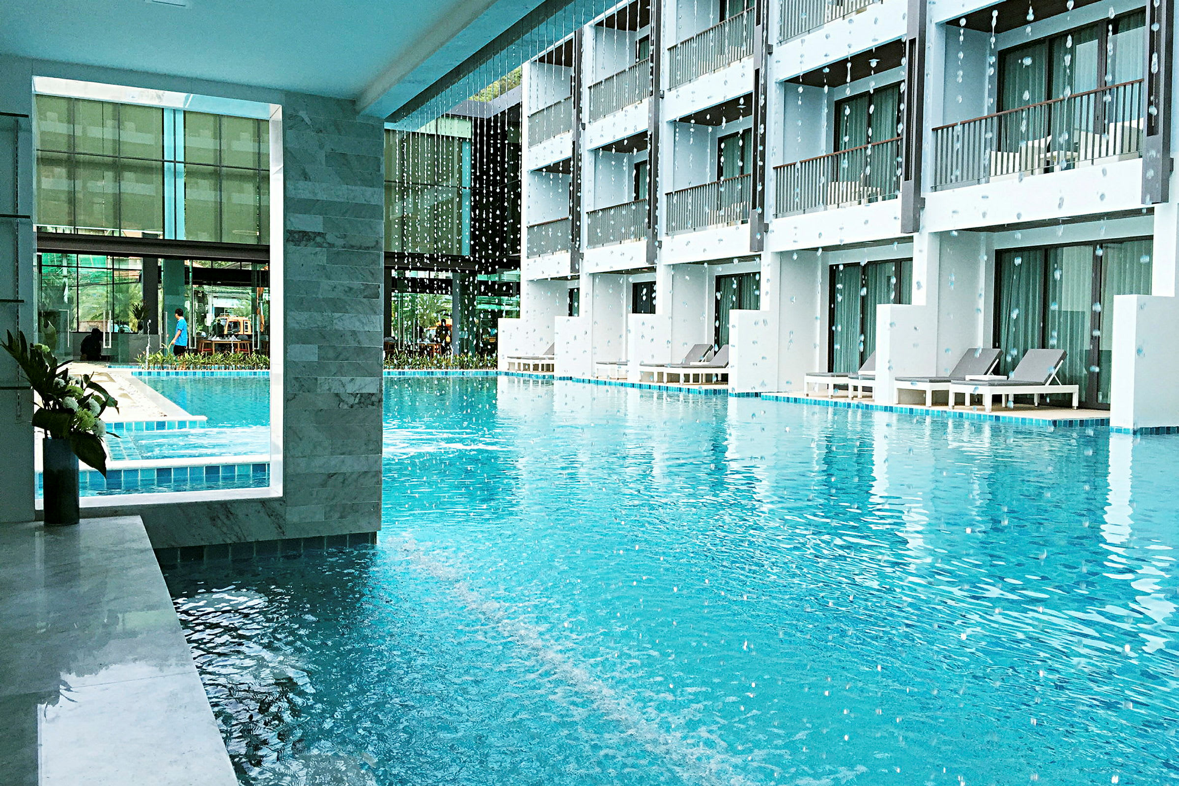 Utomhuspool vid hotell med solstolar och balkonger. (AI-genererad text)