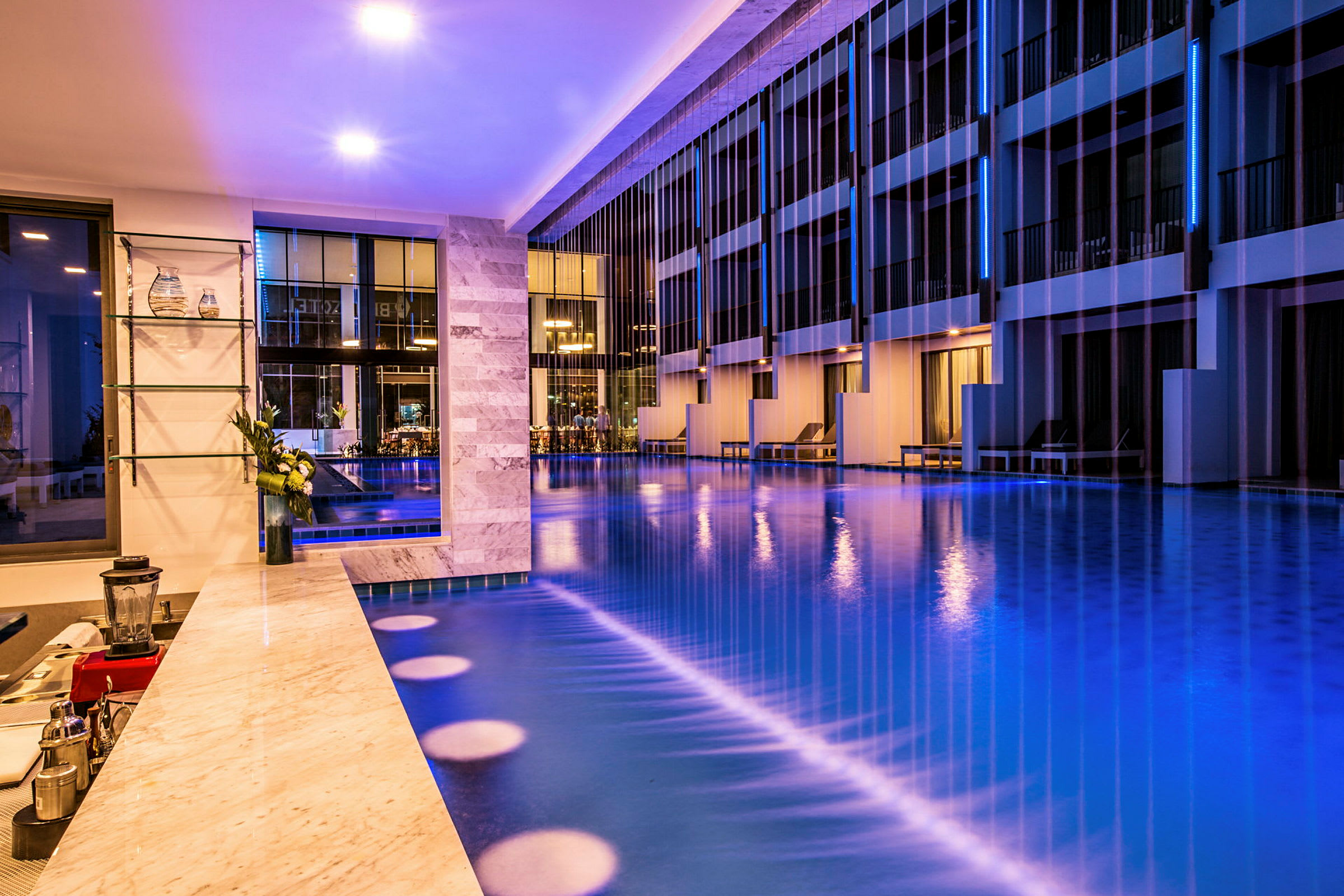 Bild av en modern hotellpool med omgivande belysning och eleganta möbler. (AI-genererad text)