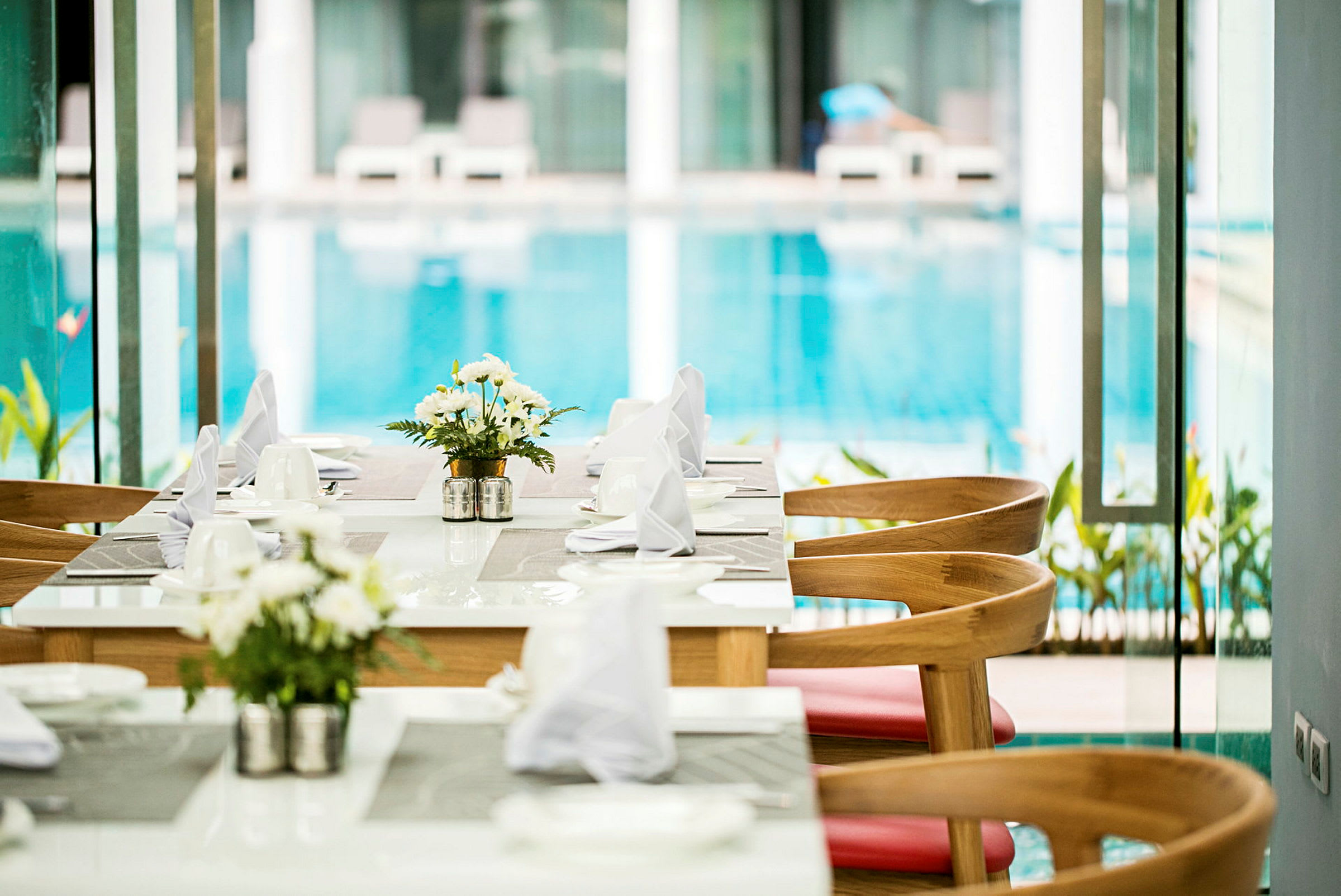 En matbord med dukar och blommor vid sidan av en pool. (AI-genererad text)
