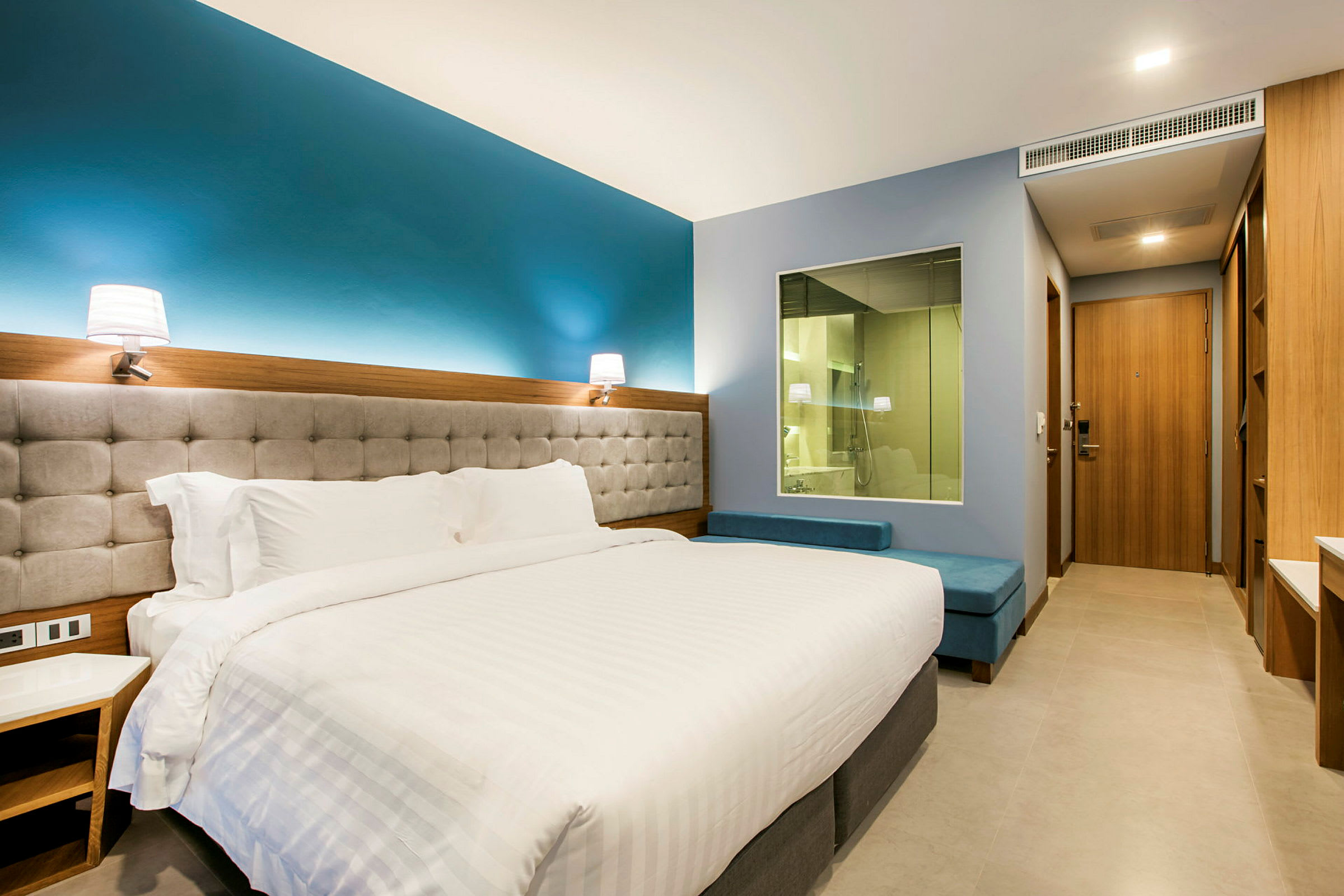 Ett hotellrum med en stor säng och fönster mot badrum. (AI-genererad text)