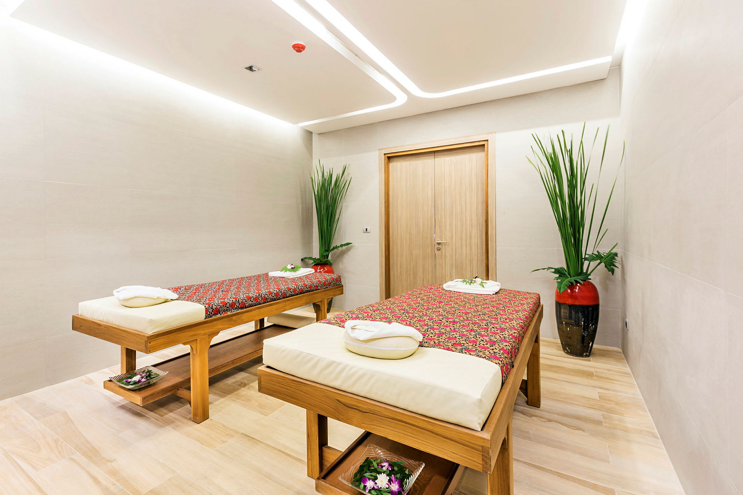 Spa-rum med två massagebänkar dekorerade med blommor och textilier. (AI-genererad text)