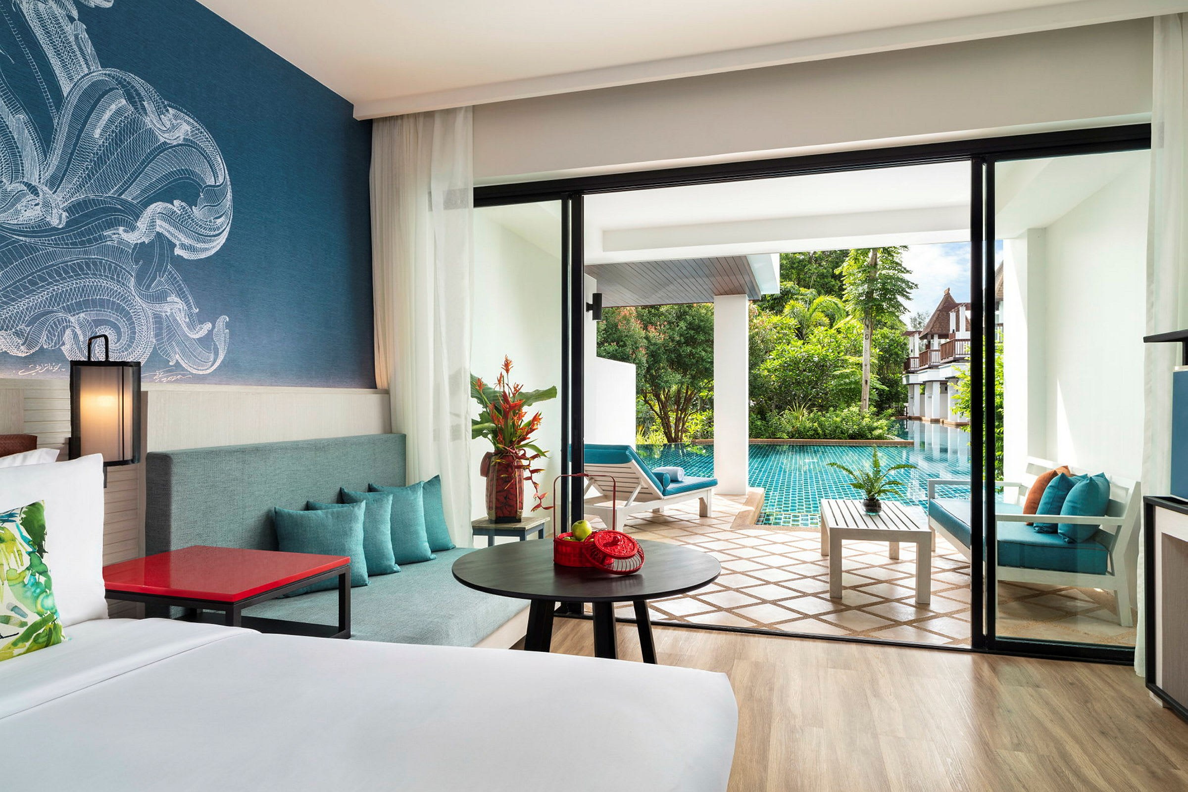 Hotellrum med moderna möbler, en stor säng, och en terrass som leder ut till en pool i ett grönskande område. (AI-genererad text)