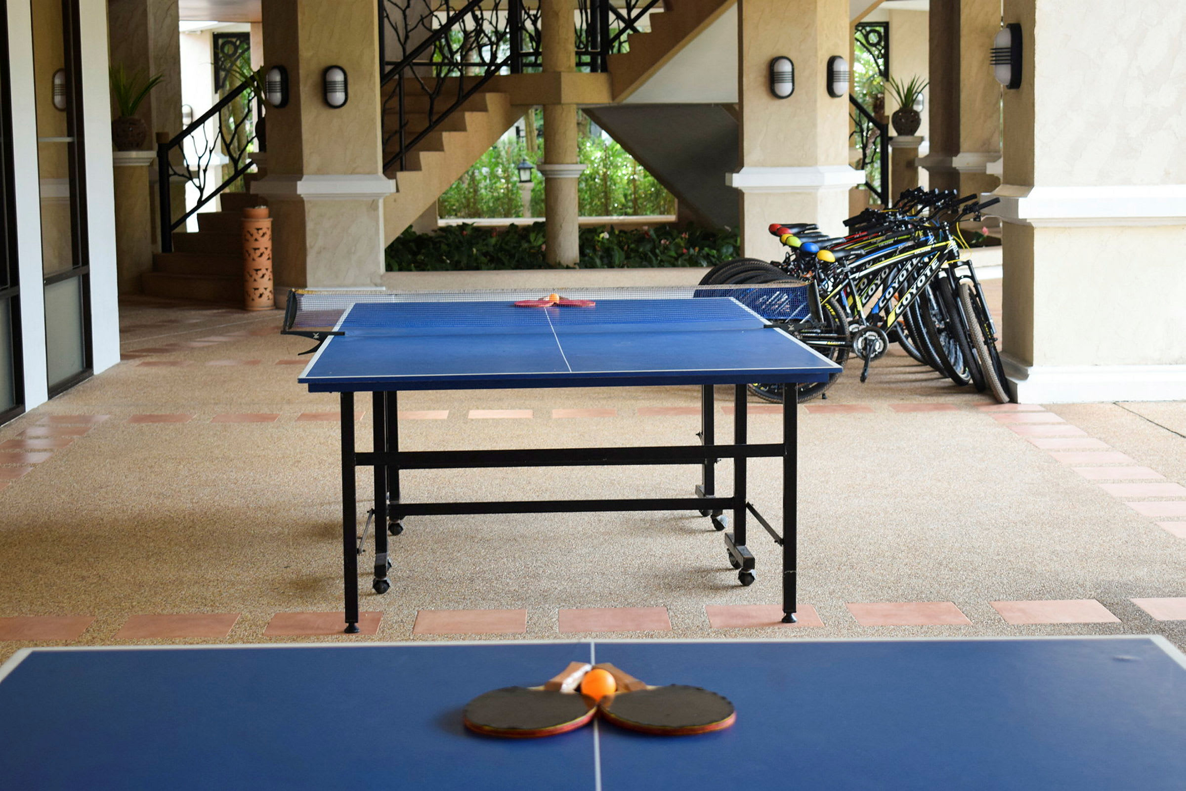 Ett bordtennisbord med racketar och boll ligger utomhus bredvid några parkerade cyklar. (AI-genererad text)