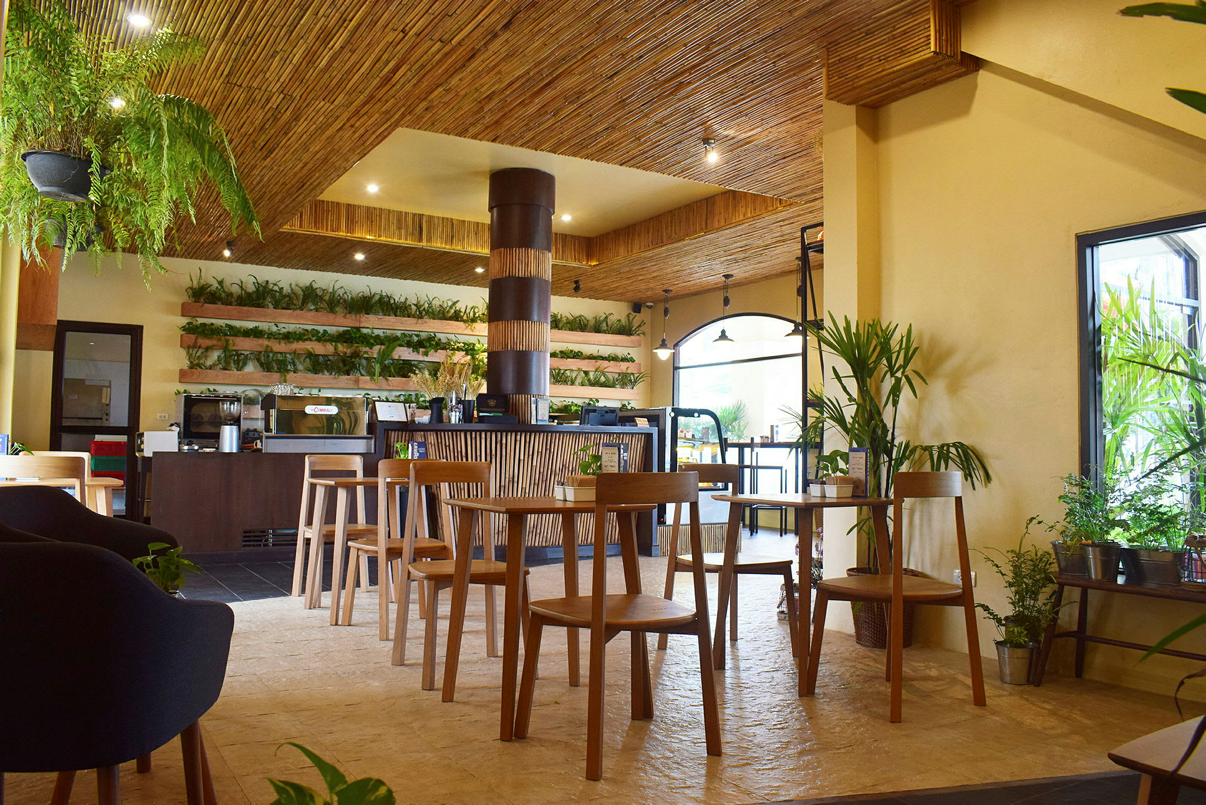 Ett café med träinredning, gröna växter och trästolar. (AI-genererad text)