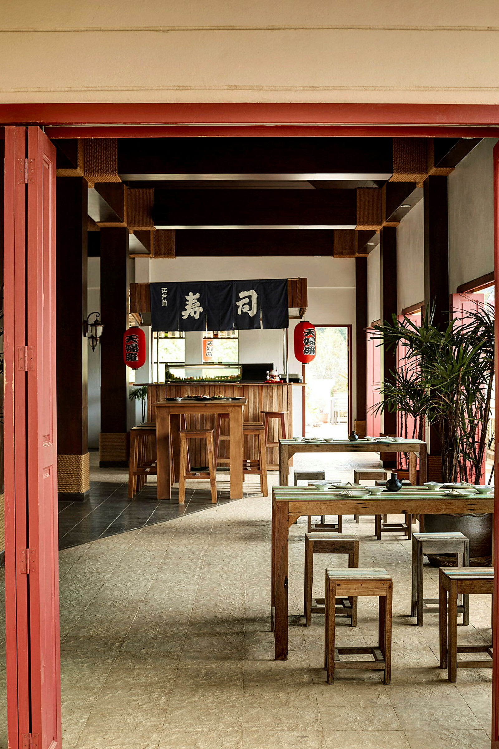 Ett rum inrett som en japansk restaurang med träbord och stolar, dekorerat med japanska lyktor och textil med japanska tecken. (AI-genererad text)