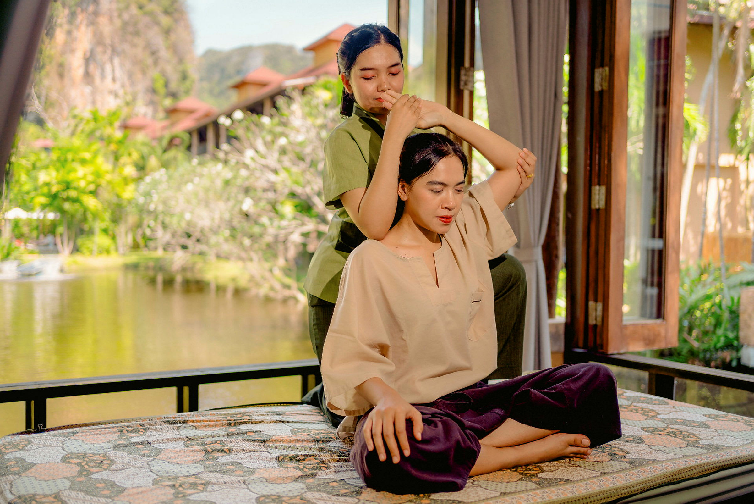 Två personer på en uteplats omgivna av natur, en av dem får en massagebehandling. (AI-genererad text)