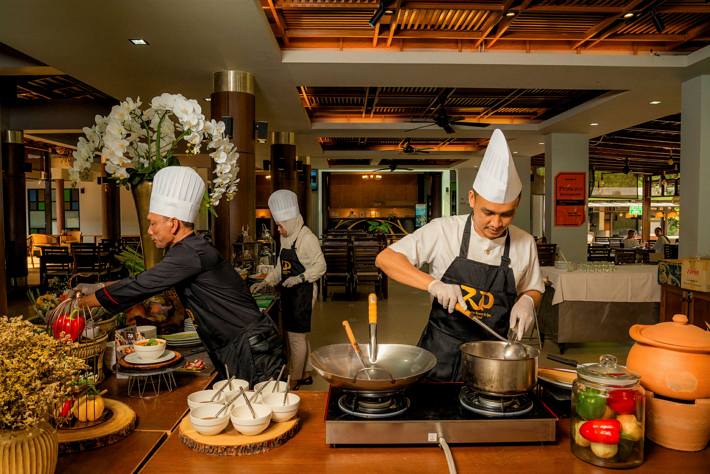 Kockar förbereder mat vid en station i en restaurang med olika ingredienser och köksutrustning. (AI-genererad text)