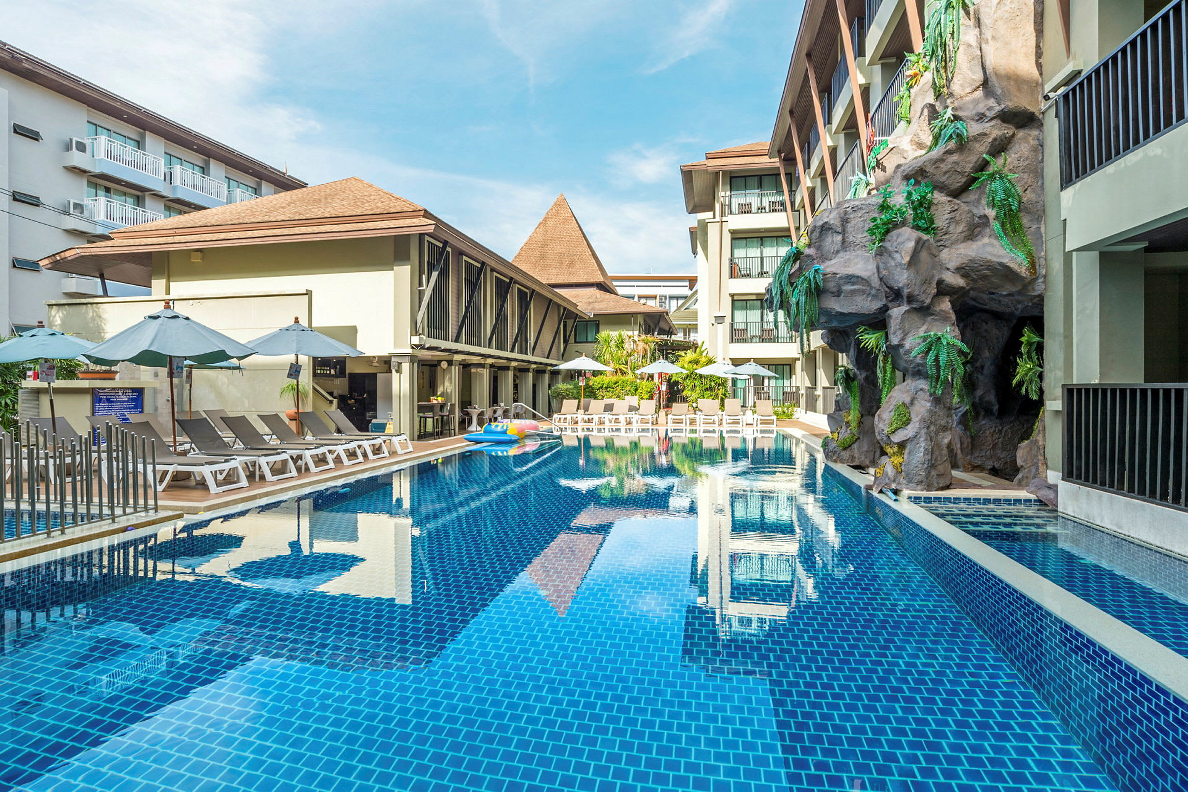 Utomhuspool vid ett hotell med solstolar och parasoll. (AI-genererad text)