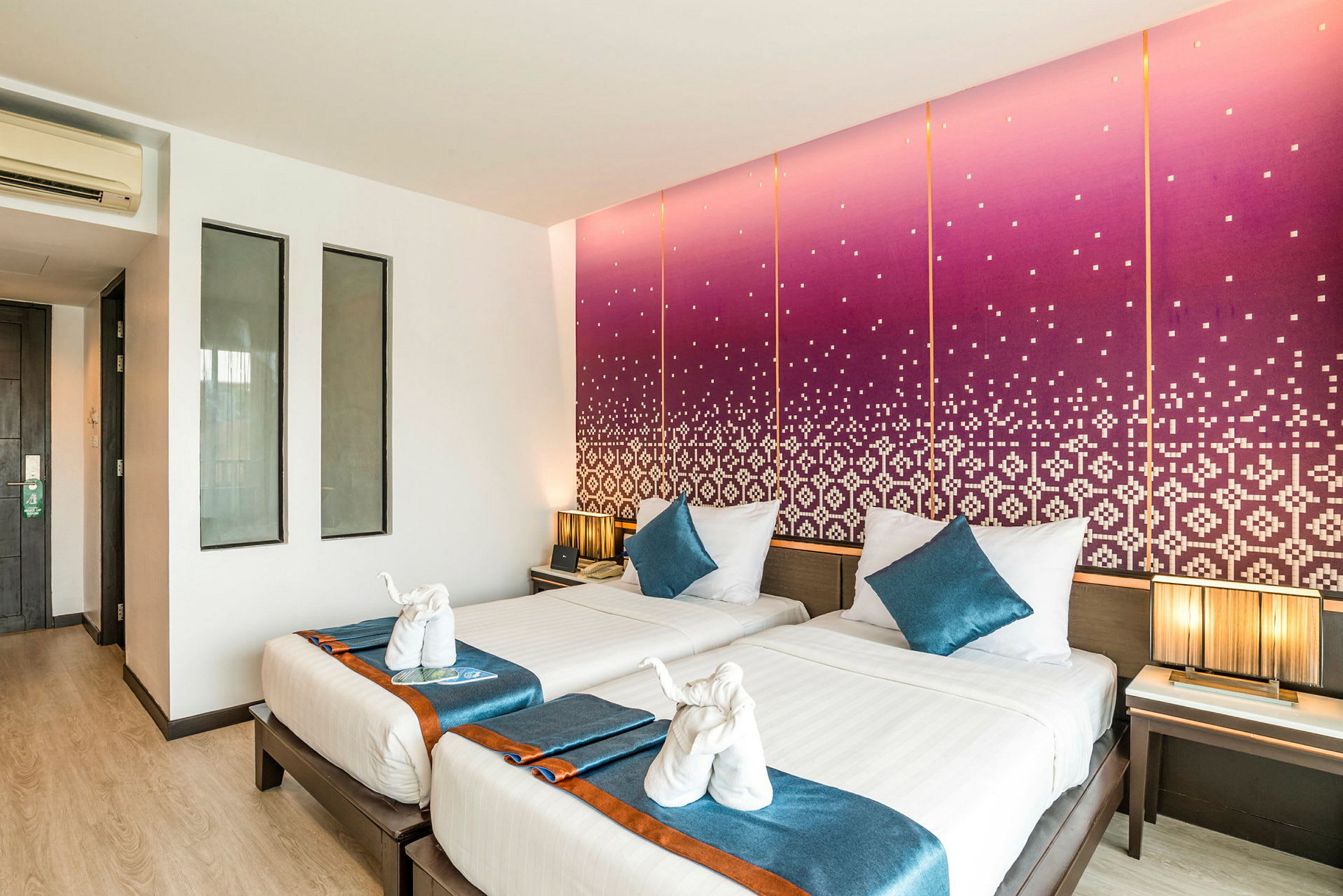 Hotellrum med två enkelsängar, färgglada sängkläder och väggdekorationer med ett mönster. (AI-genererad text)