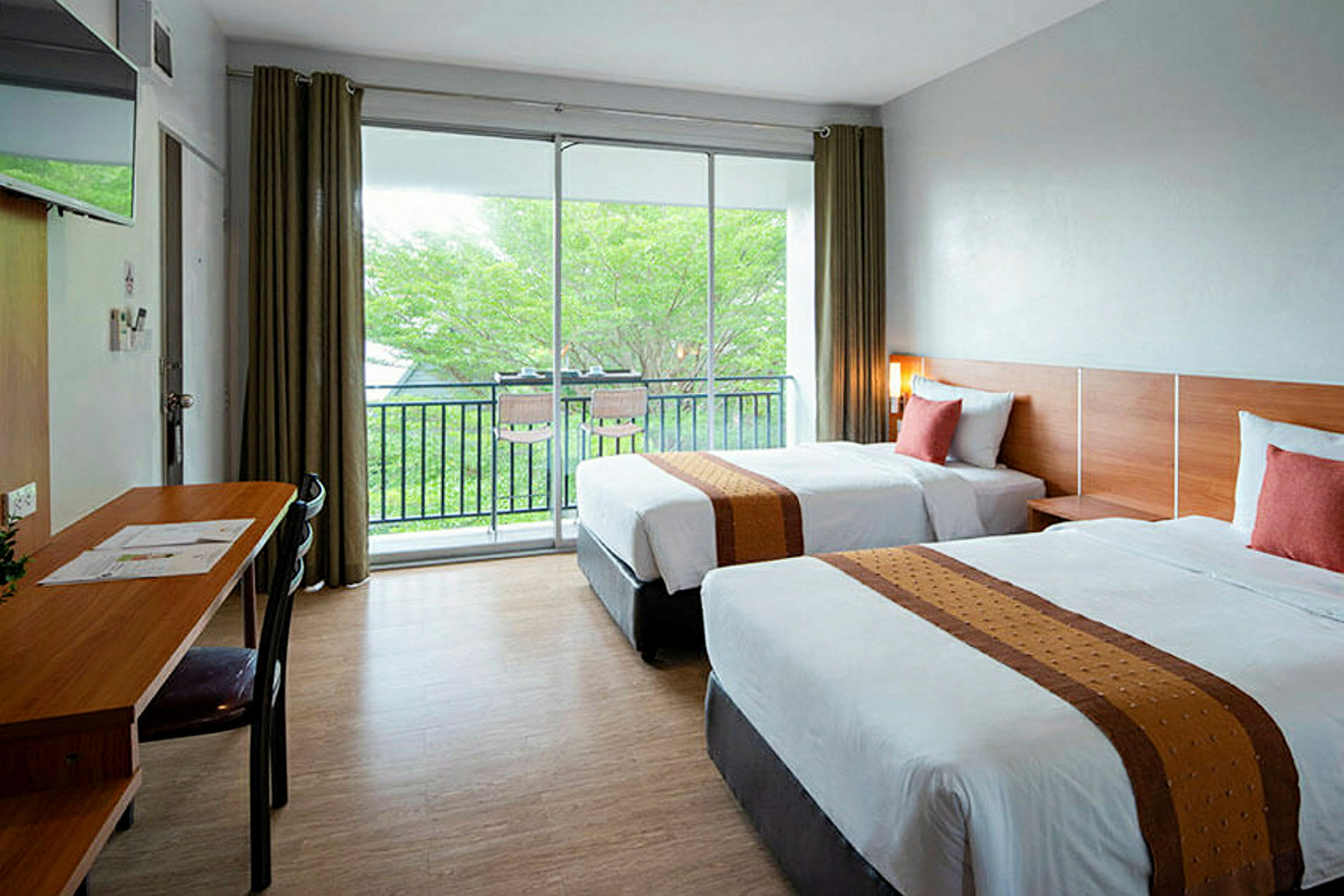 Två sängar i ett hotellrum med stora fönster och utsikt mot grönska. (AI-genererad text)