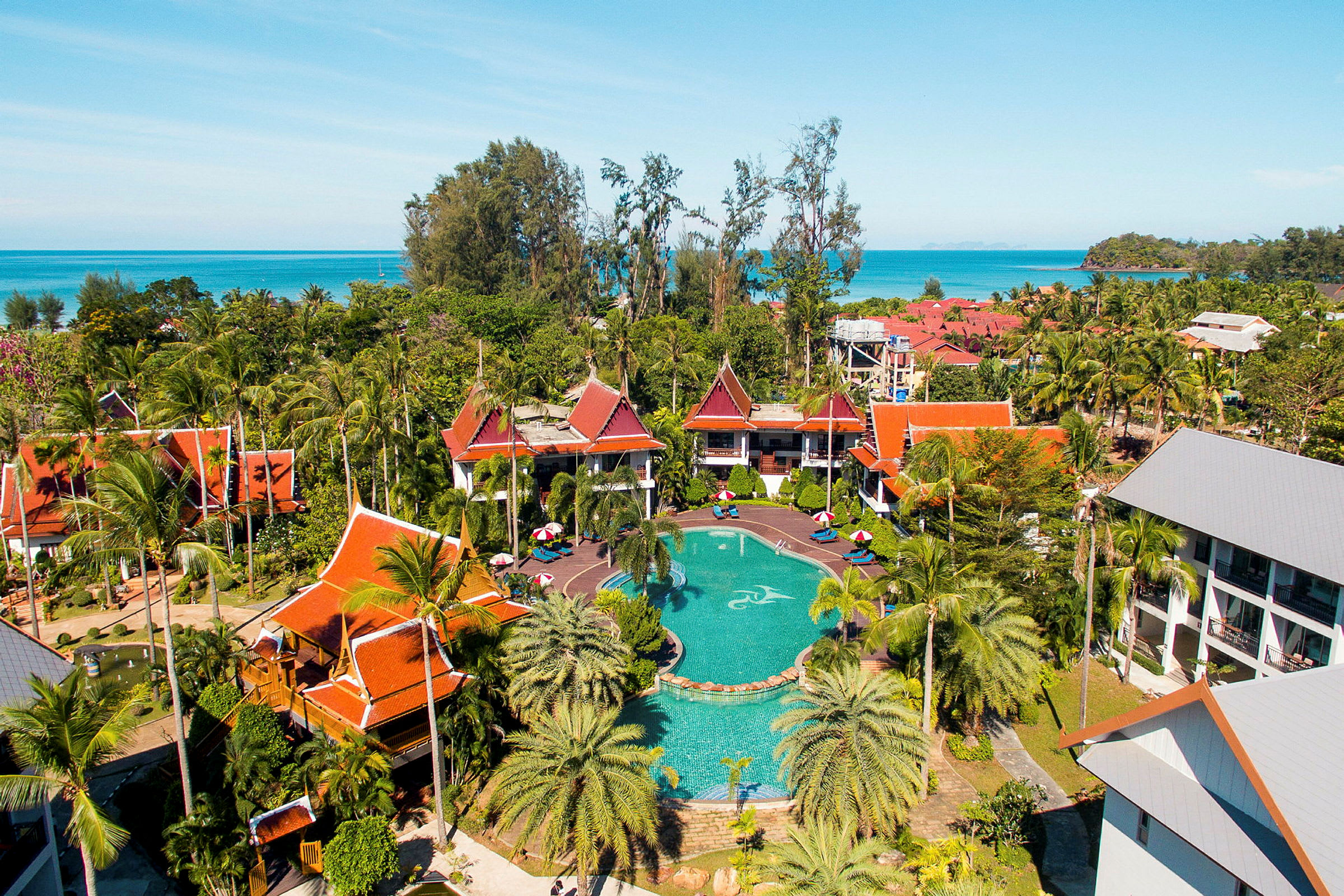 Ett semesterresort med pool, omgiven av tropiska byggnader samt palmer och grönska. (AI-genererad text)