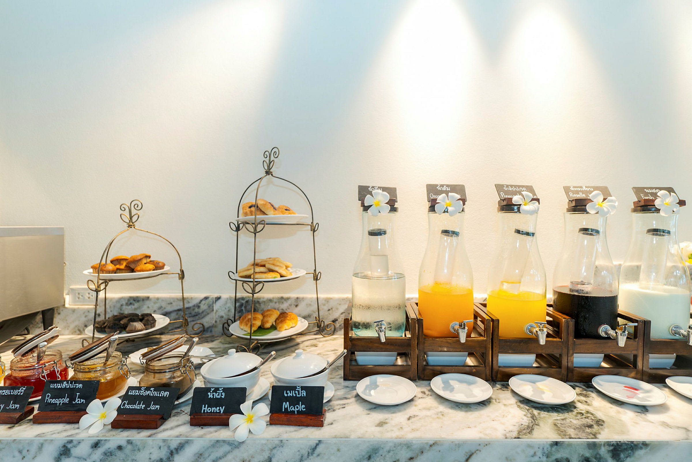 Frukostbuffé med sylt, honung, lönnsirap och bakverk samt juiceflaskor. (AI-genererad text)