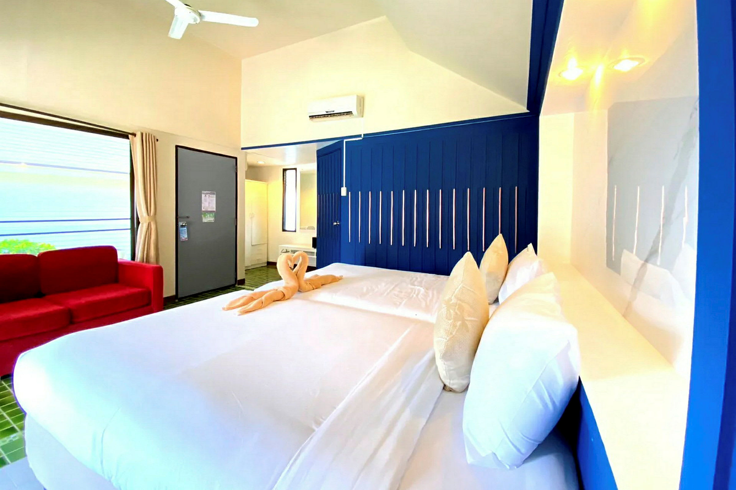 Hotellrum med dubbelsäng, blå vägg och en röd soffa. (AI-genererad text)