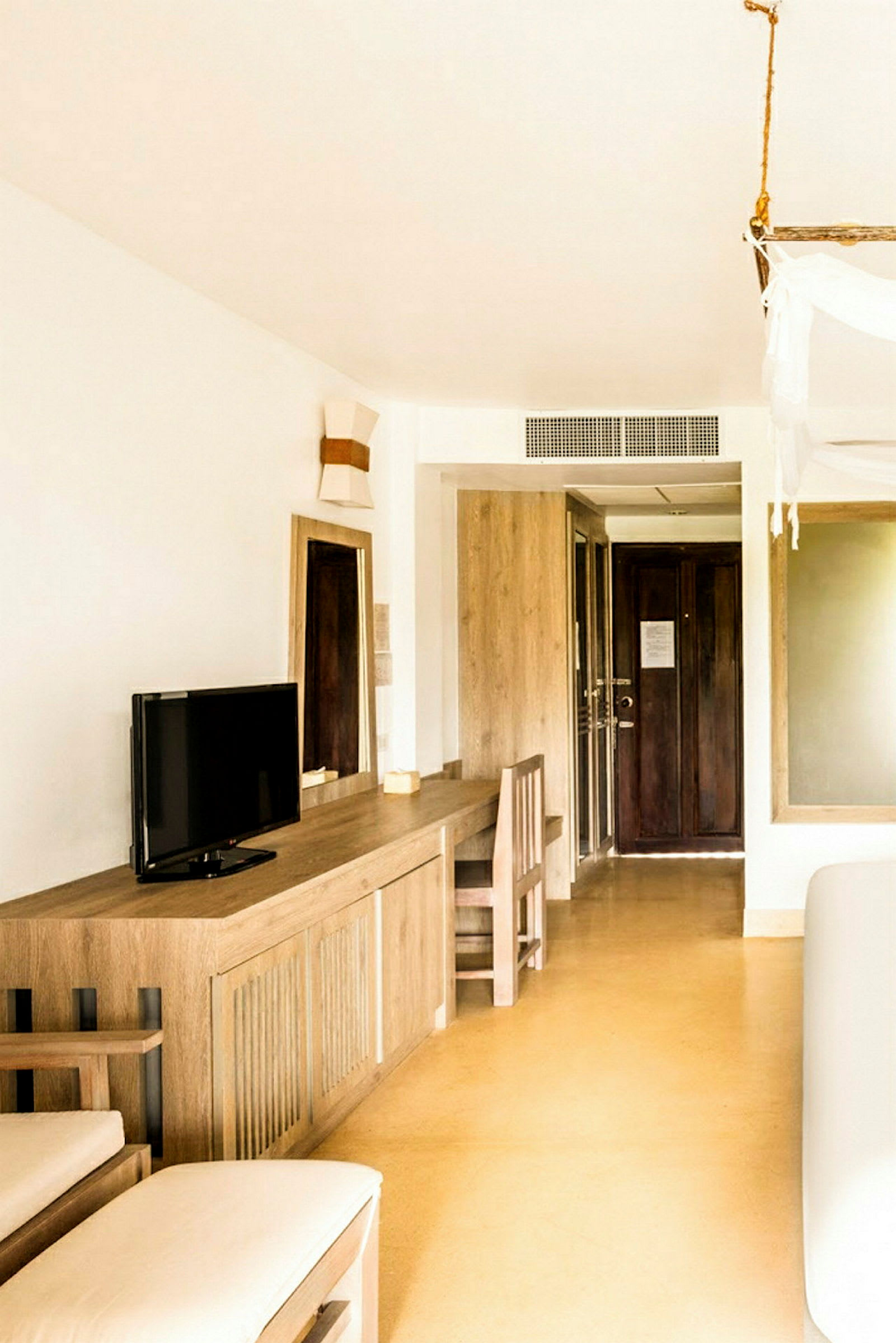 Ett hotellrum med en minimalistisk inredning, inklusive ett skrivbord, en stol, och en liten TV. (AI-genererad text)