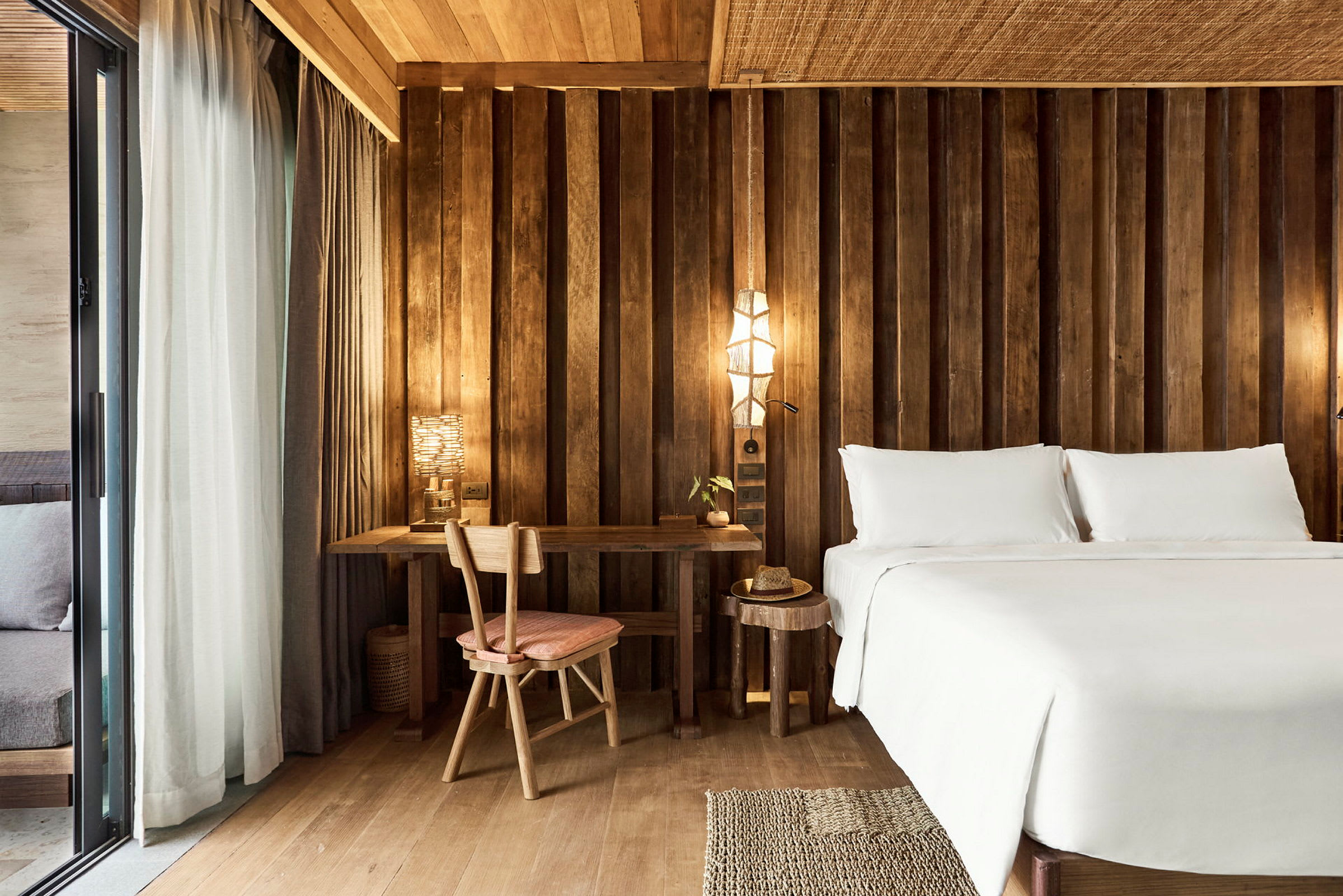 Ett hotellrum med en säng, ett skrivbord och en stol i ett rum med träpaneler. (AI-genererad text)
