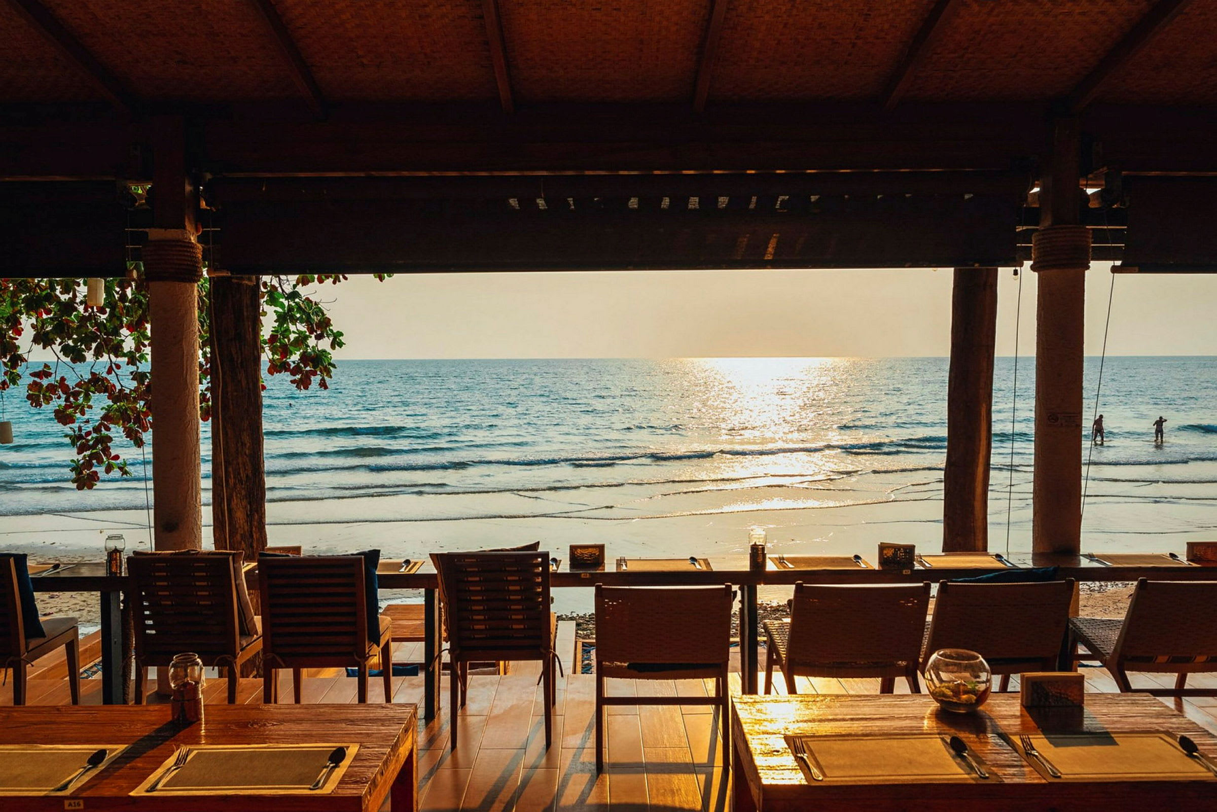 En restaurang med utsikt över stranden och havet i solnedgången. (AI-genererad text)