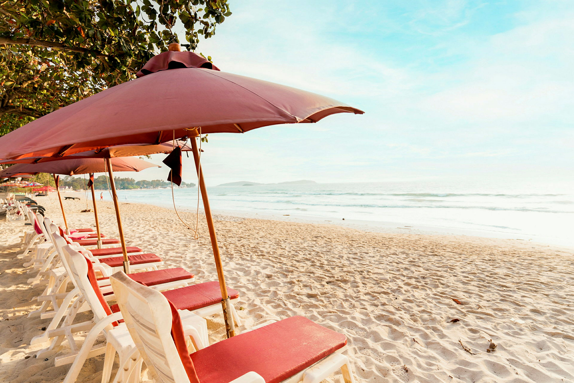 Strand med solstolar och parasoller i en rad vid havet. (AI-genererad text)