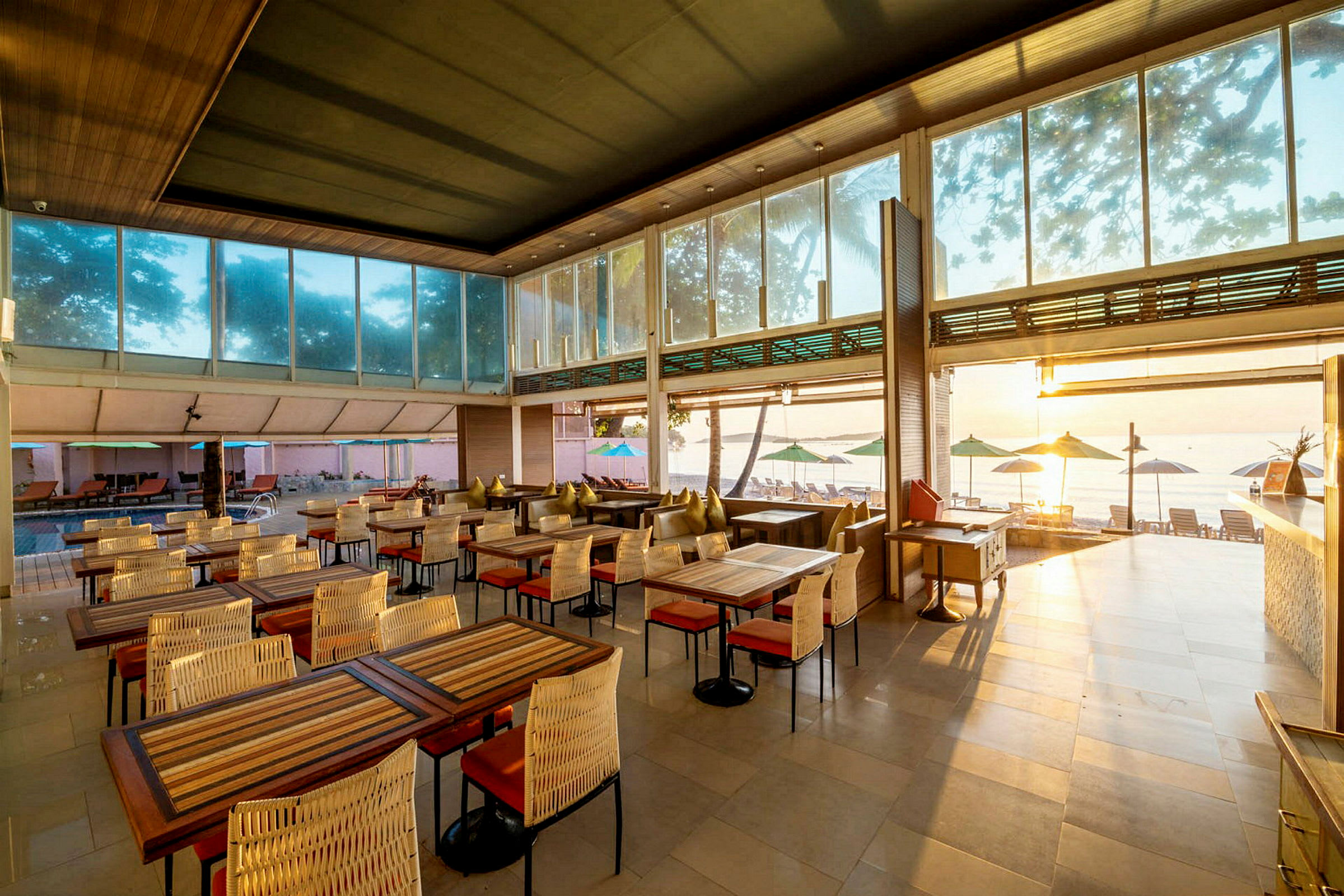 En restaurang med utsikt över stranden, möblerad med bord och stolar. (AI-genererad text)