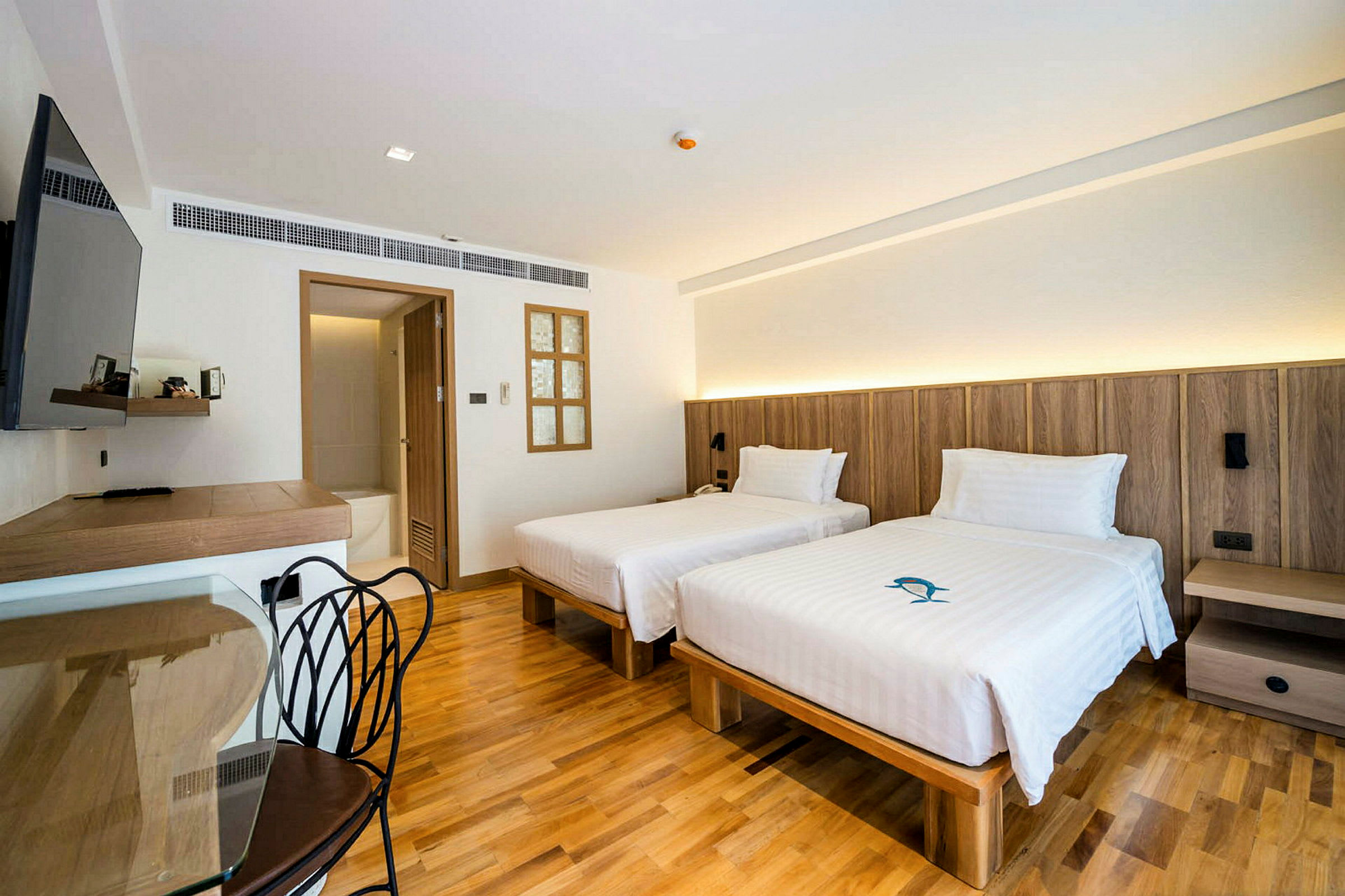Hotellrum med två enkelsängar, trägolv och möbler i modern design. (AI-genererad text)