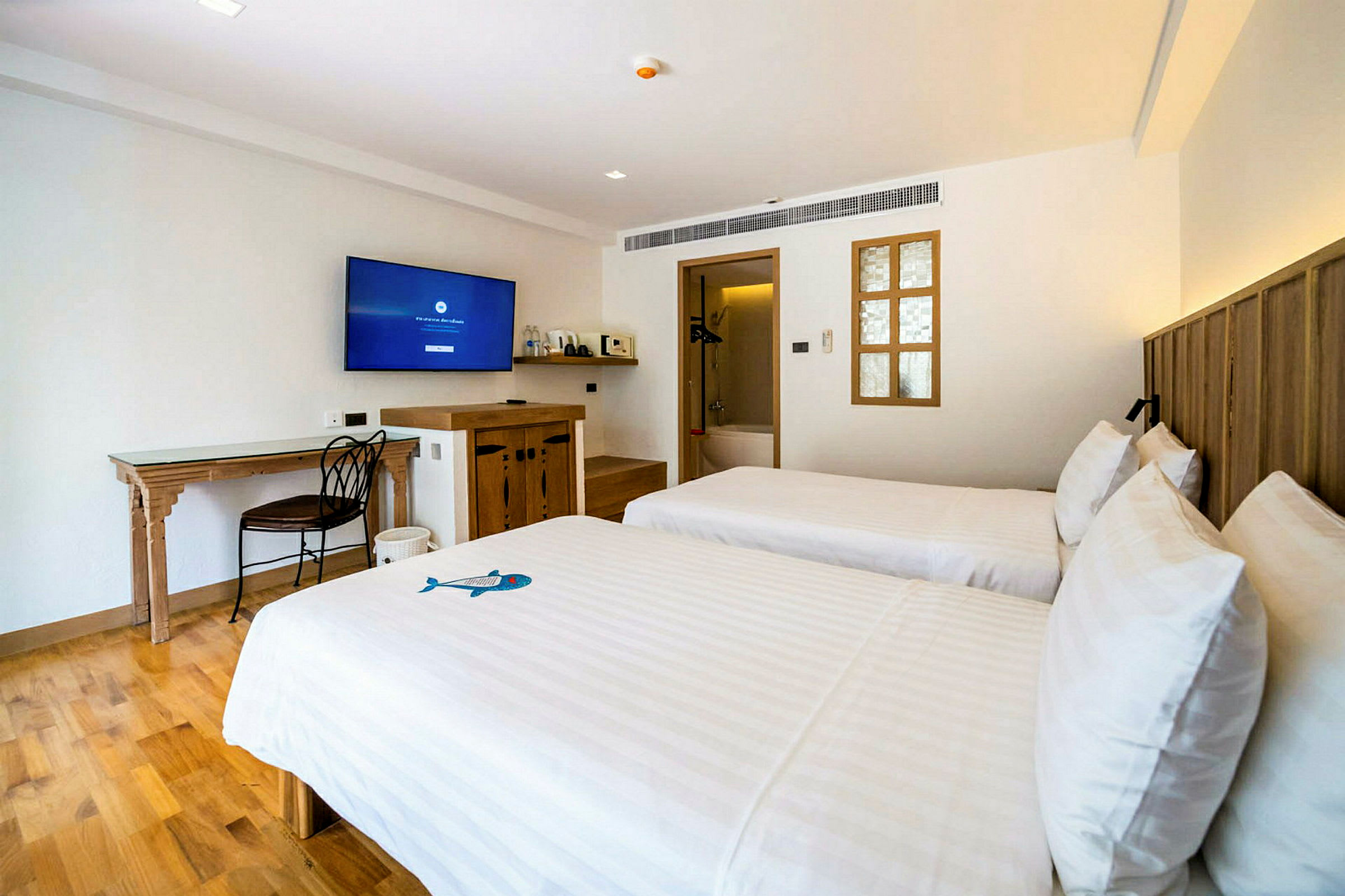Ett hotellrum med två enkelsängar, en tv på väggen och hårda trämöbler. (AI-genererad text)