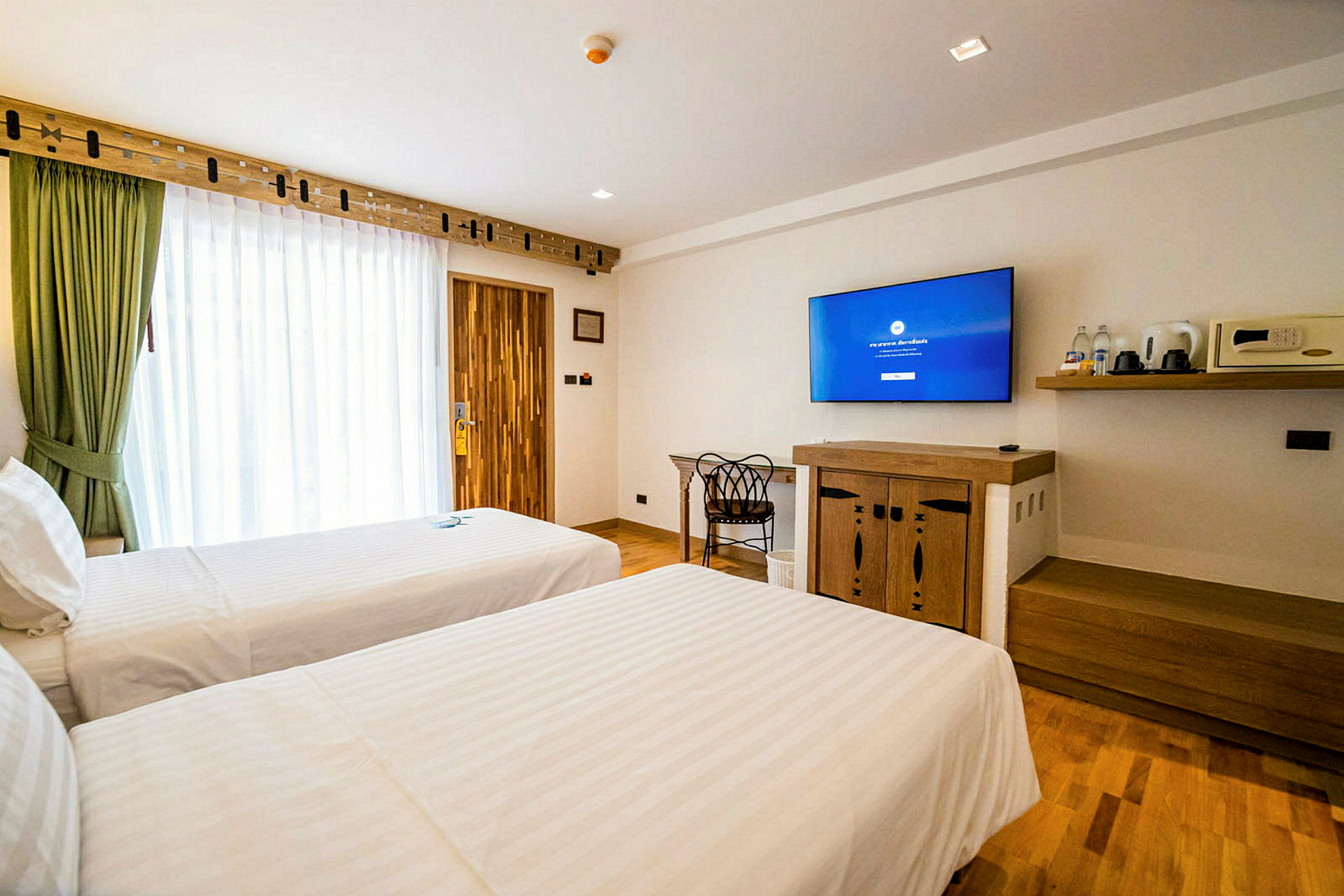 Ett hotellrum med två enkelsängar, en TV på väggen och en förvaringshylla. (AI-genererad text)