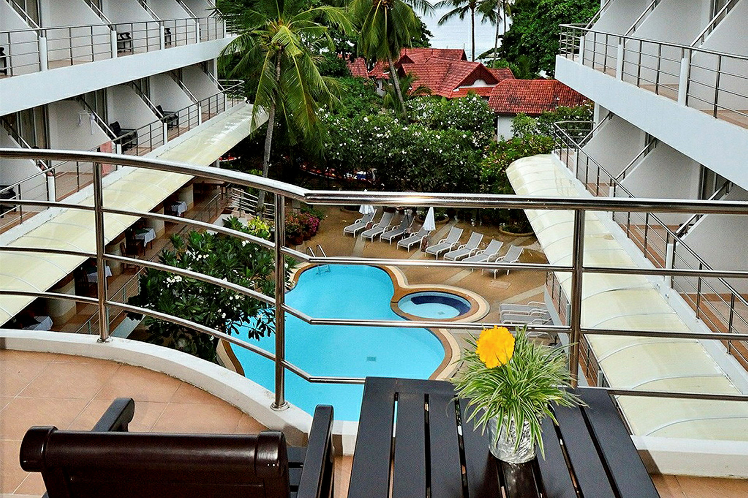 Bild av en hotellpool med omgärdade solsängar, sett från en balkong med utsikt över området. (AI-genererad text)