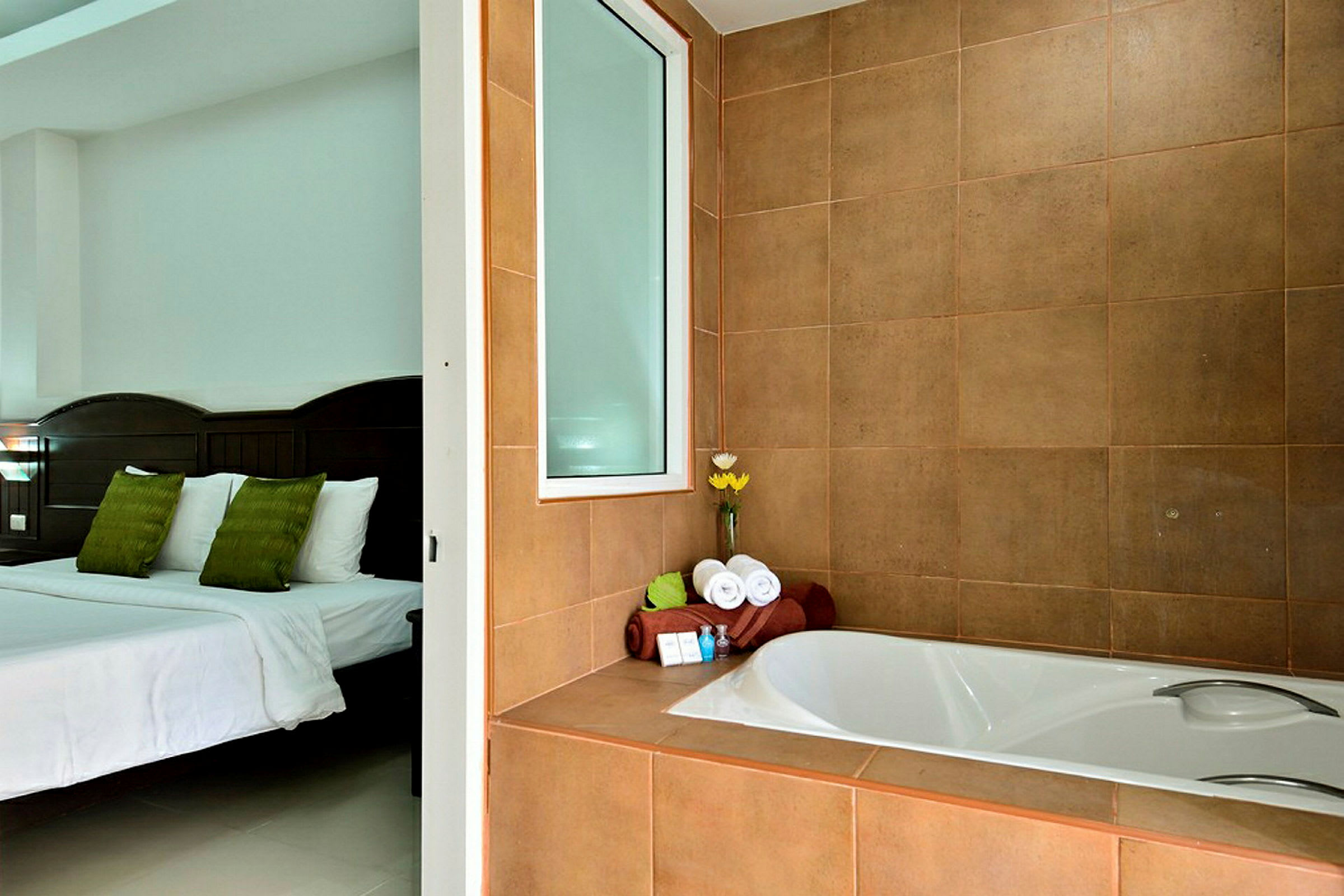 Bilden visar ett hotellrum med en säng och en jacuzzi i förgrunden. På badkarskanten ligger handdukar och toalettartiklar. (AI-genererad text)