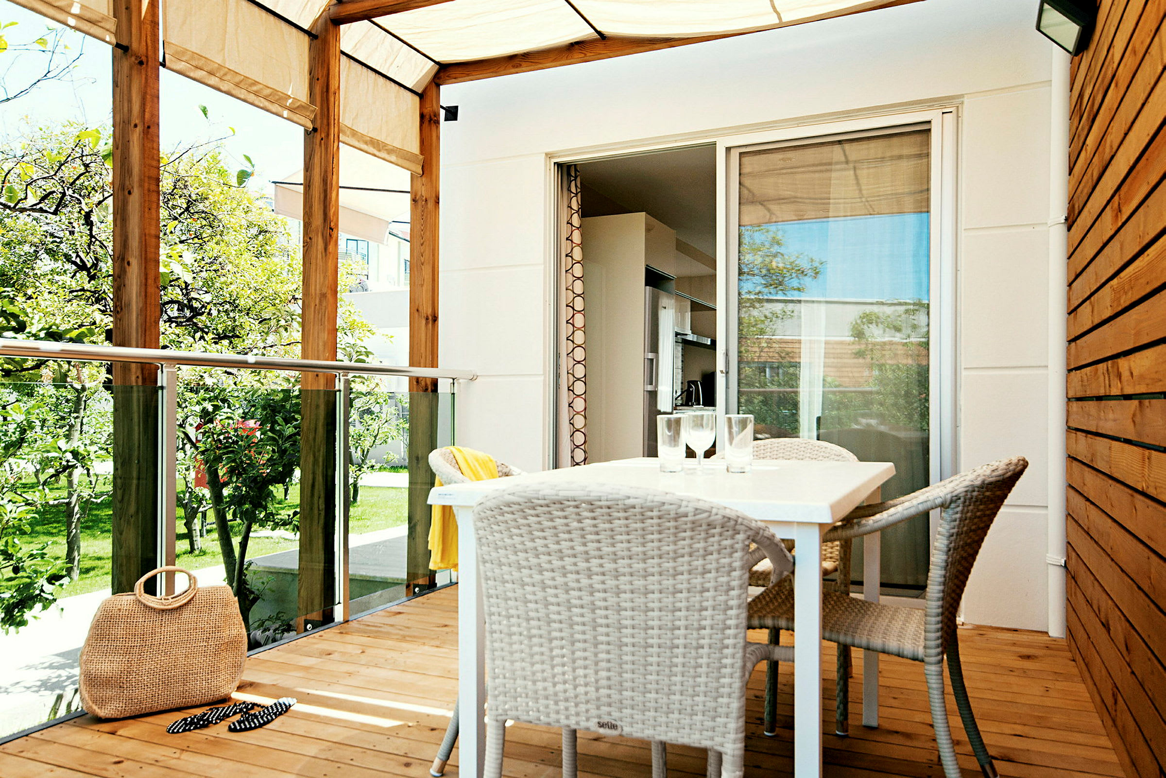 En veranda med tak, bord och stolar samt utsikt mot en trädgård. (AI-genererad text)