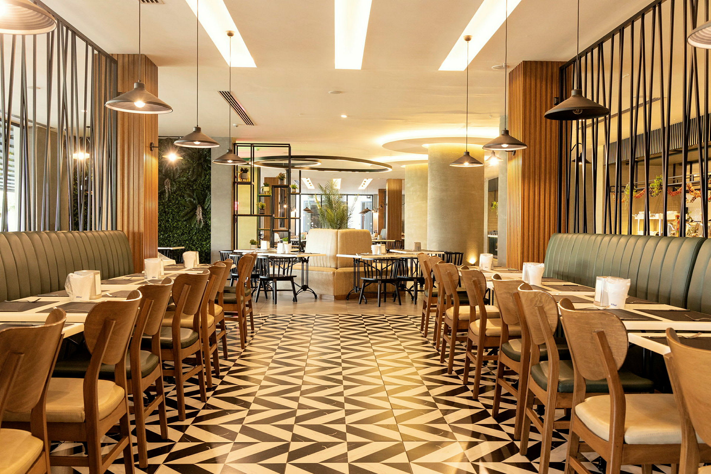 En modern restaurang med geometriska golvplattor, stilfull inredning och bord organiserade för servering. (AI-genererad text)