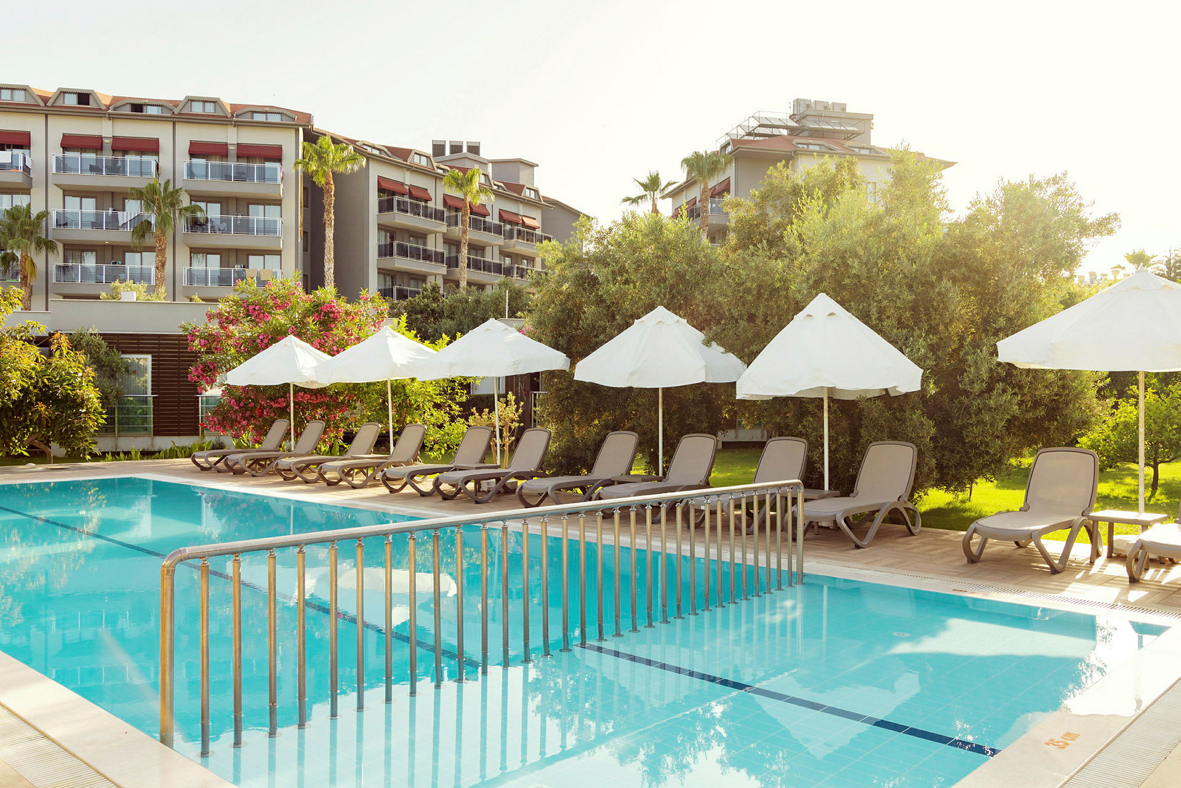 Stolar och parasoller vid en pool, med ett hotell i bakgrunden. (AI-genererad text)