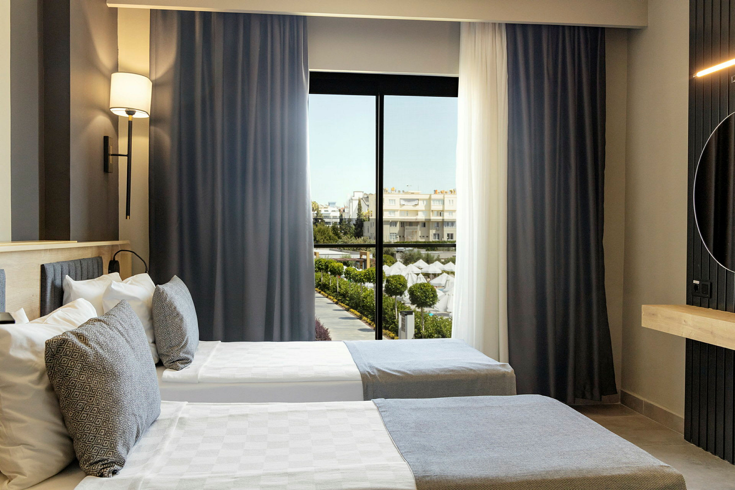 Hotellrum med två enkelsängar och fönster med utsikt mot ett poolområde. (AI-genererad text)