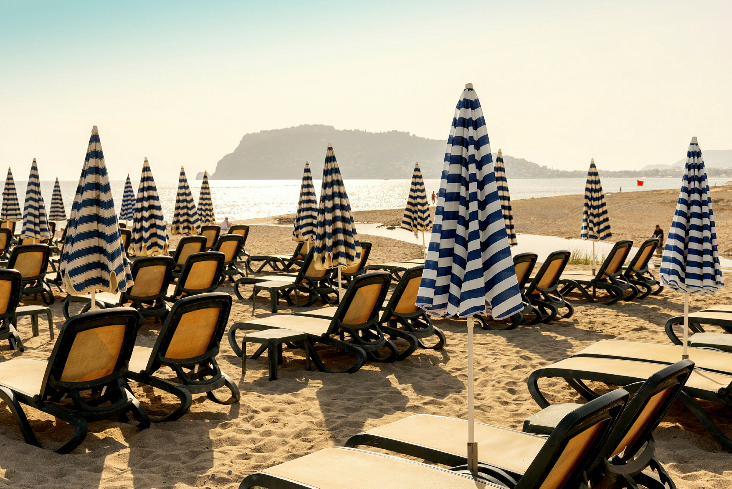 Strand med solstolar och randiga parasoller. (AI-genererad text)
