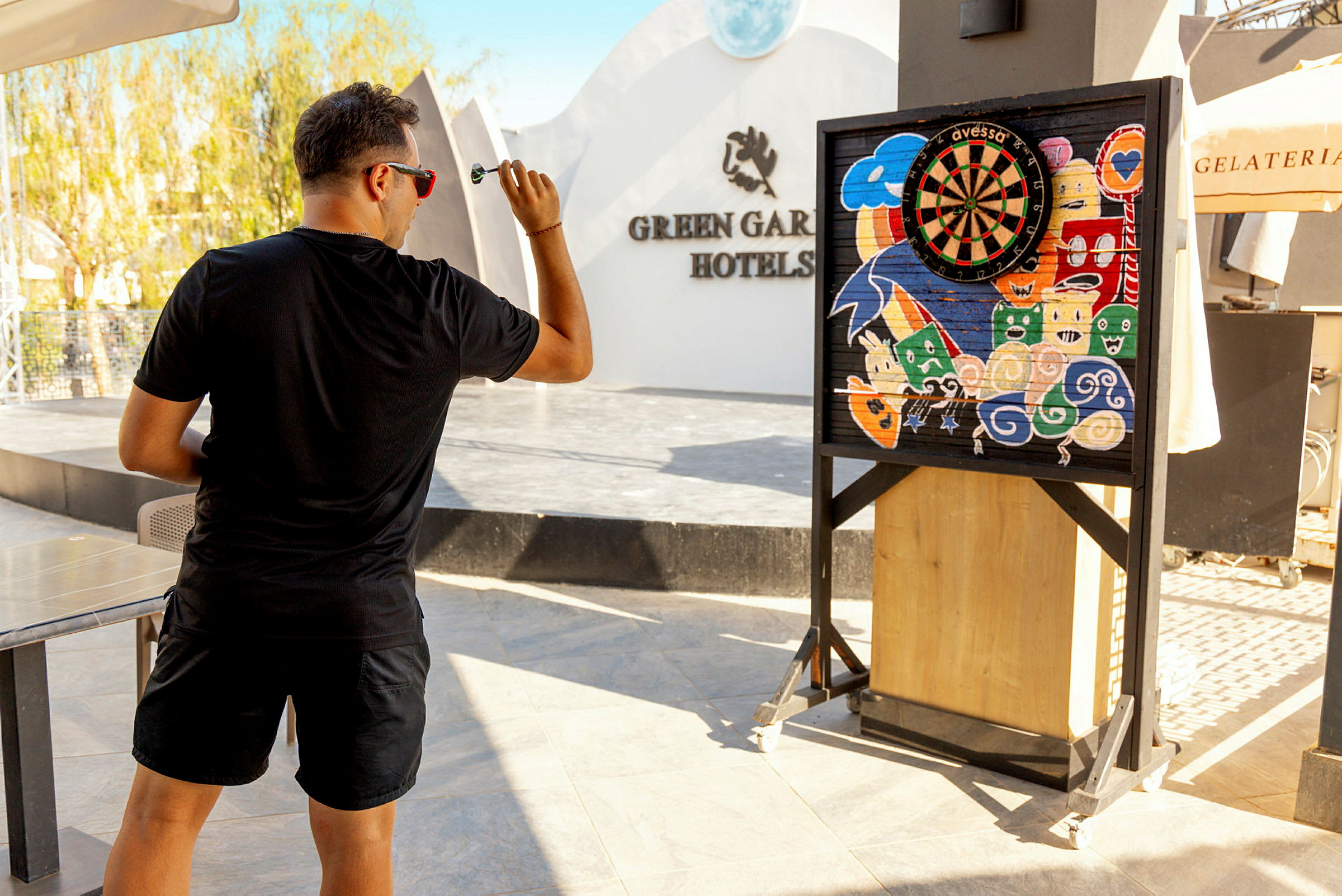 Man spelar dart framför en färgglad darttavla på hotellet. (AI-genererad text)
