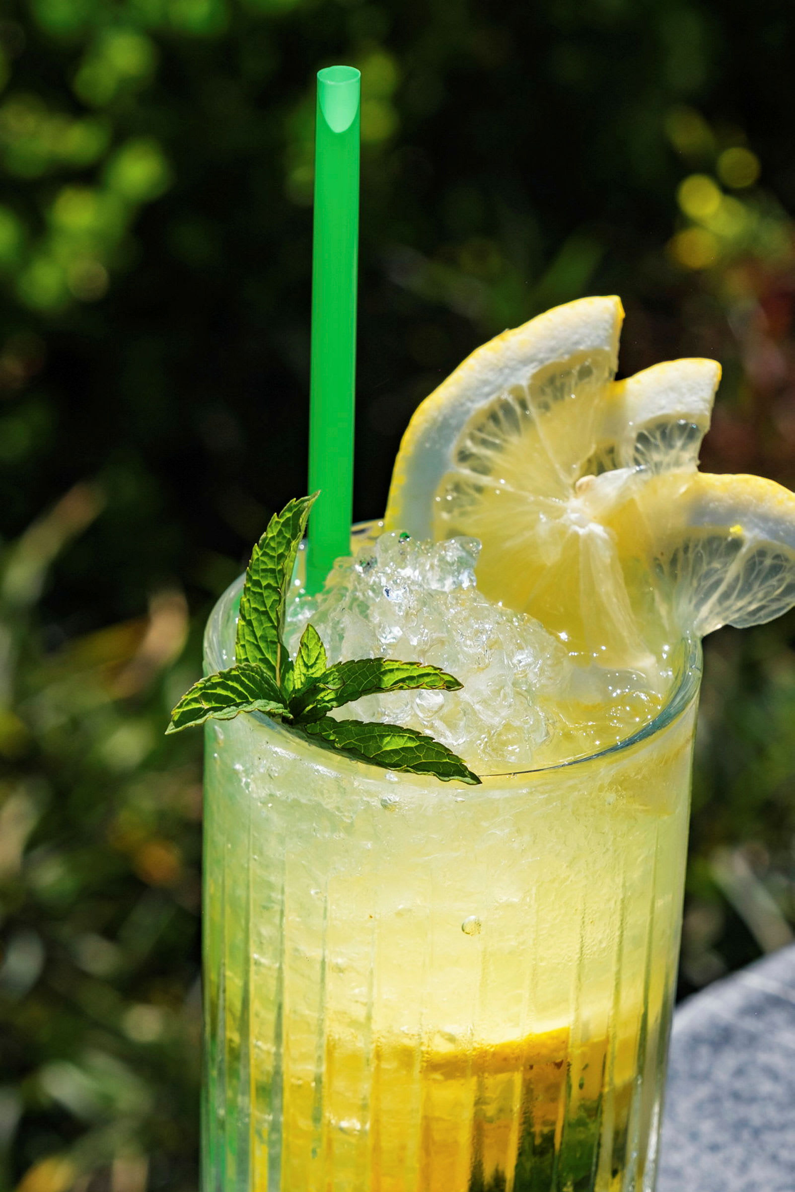 Närbild av ett glas med gul dryck, is, citron och mynta. (AI-genererad text)