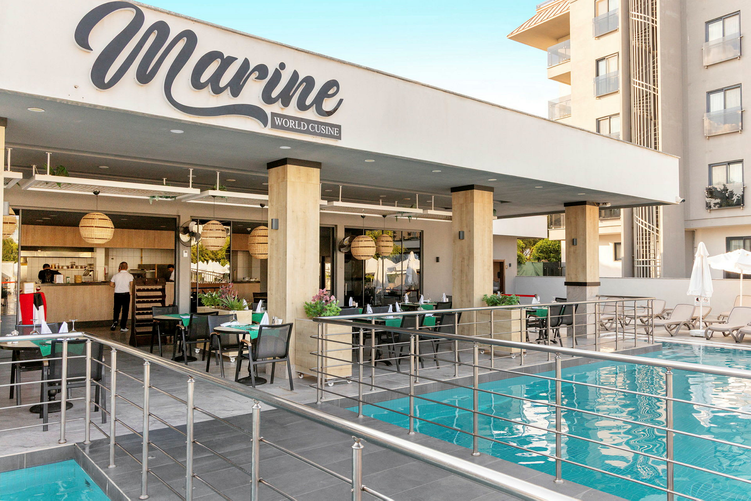 En restaurang vid namn Marine World Cuisine belägen bredvid en pool med sittplatser och bord. (AI-genererad text)