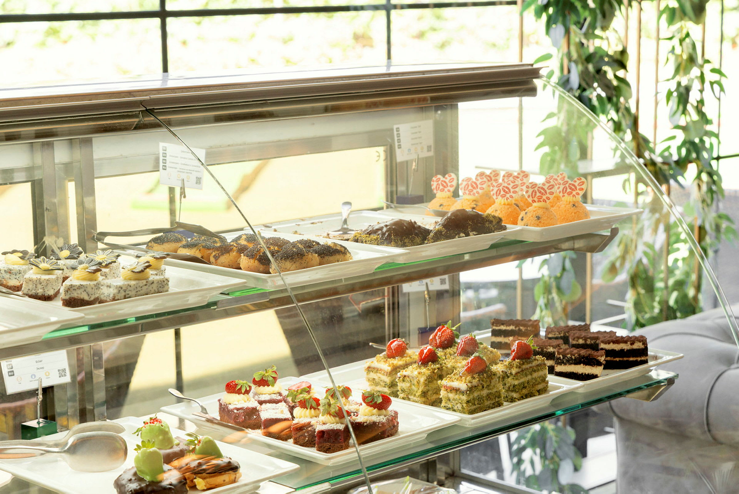Ett vitrinskåp med olika bakverk och desserter på fat. (AI-genererad text)