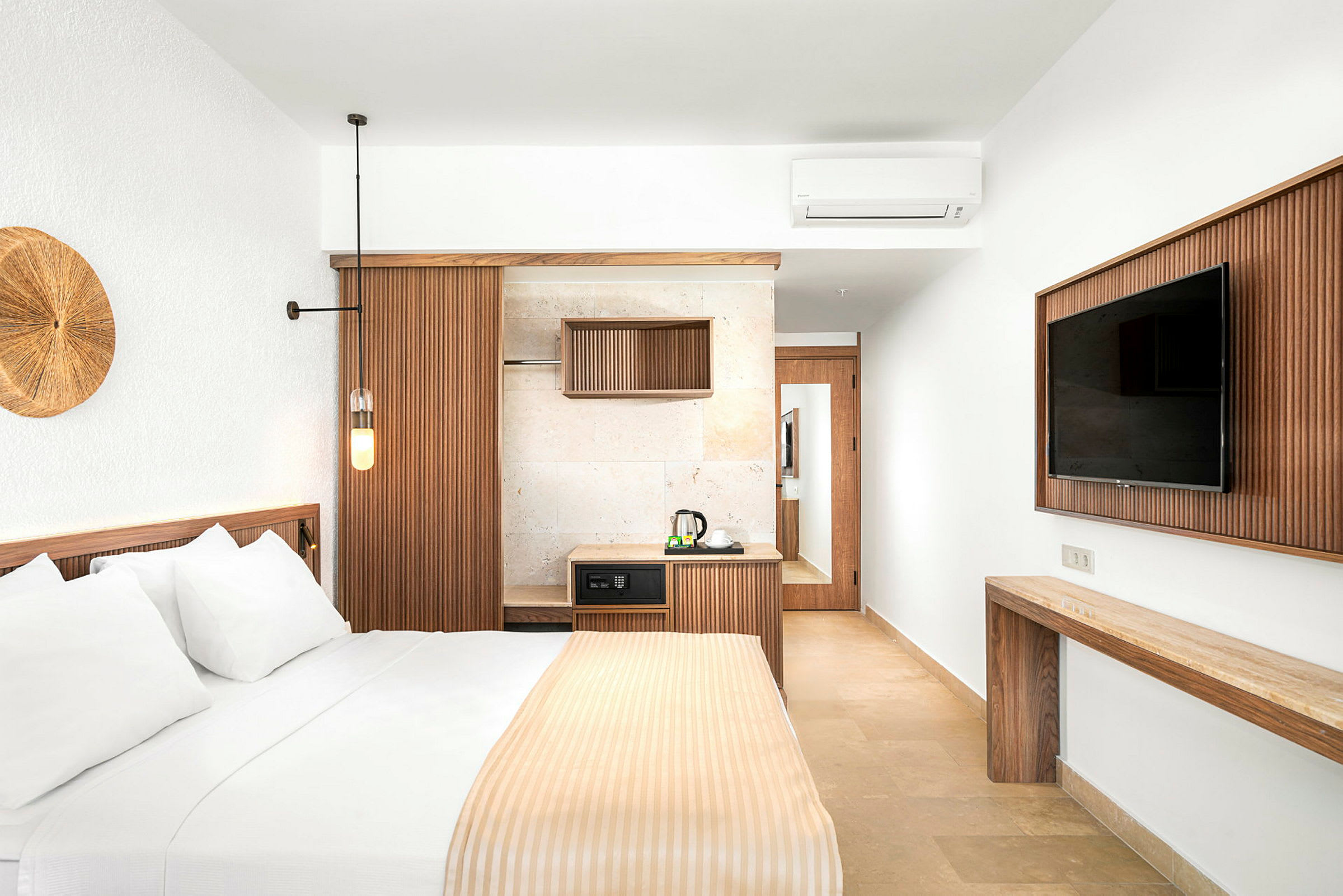 Ett stilfullt hotellrum med en säng, en TV och en liten kökshörna. (AI-genererad text)