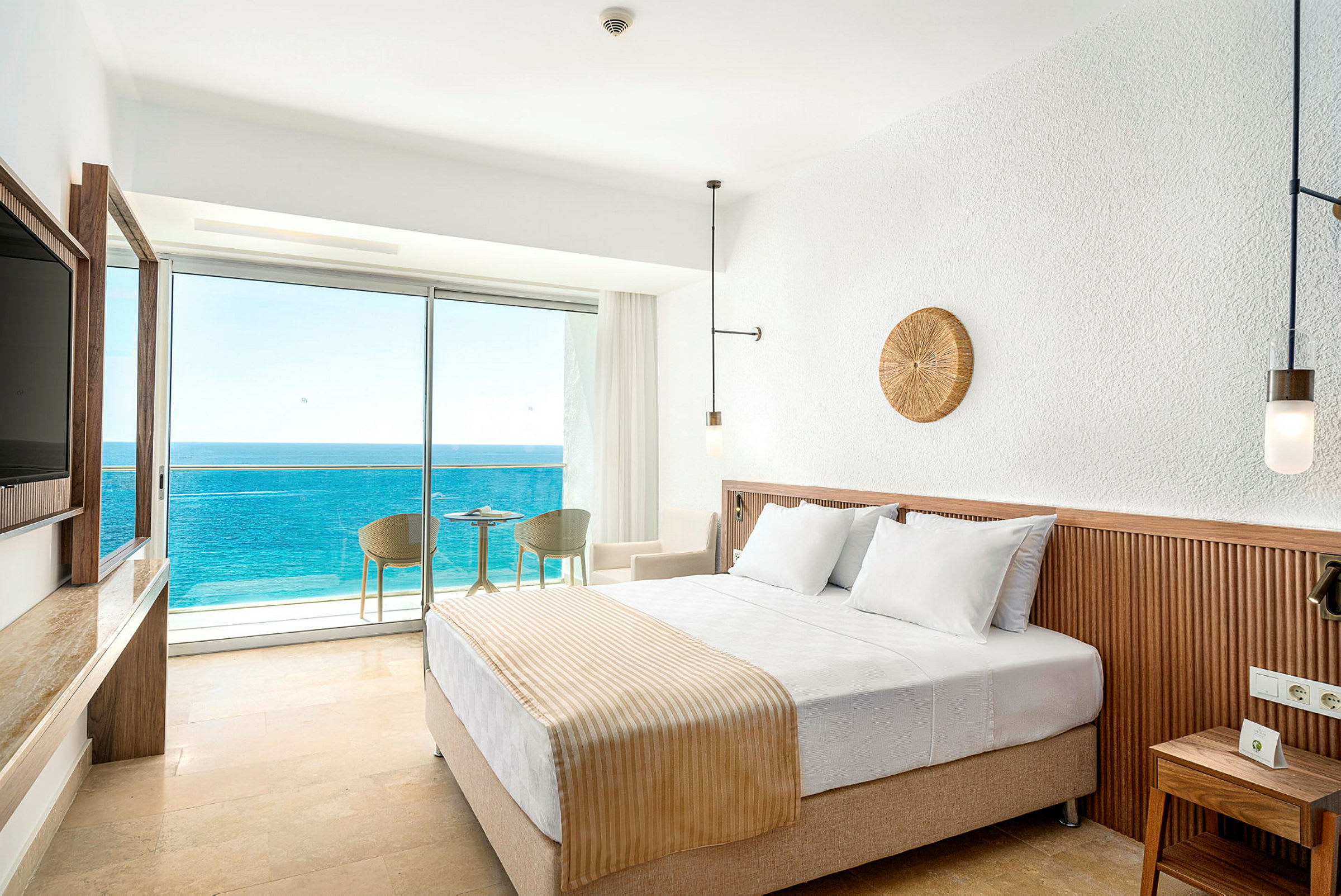 Hotellrum med en dubbelsäng och balkong med utsikt över havet. (AI-genererad text)