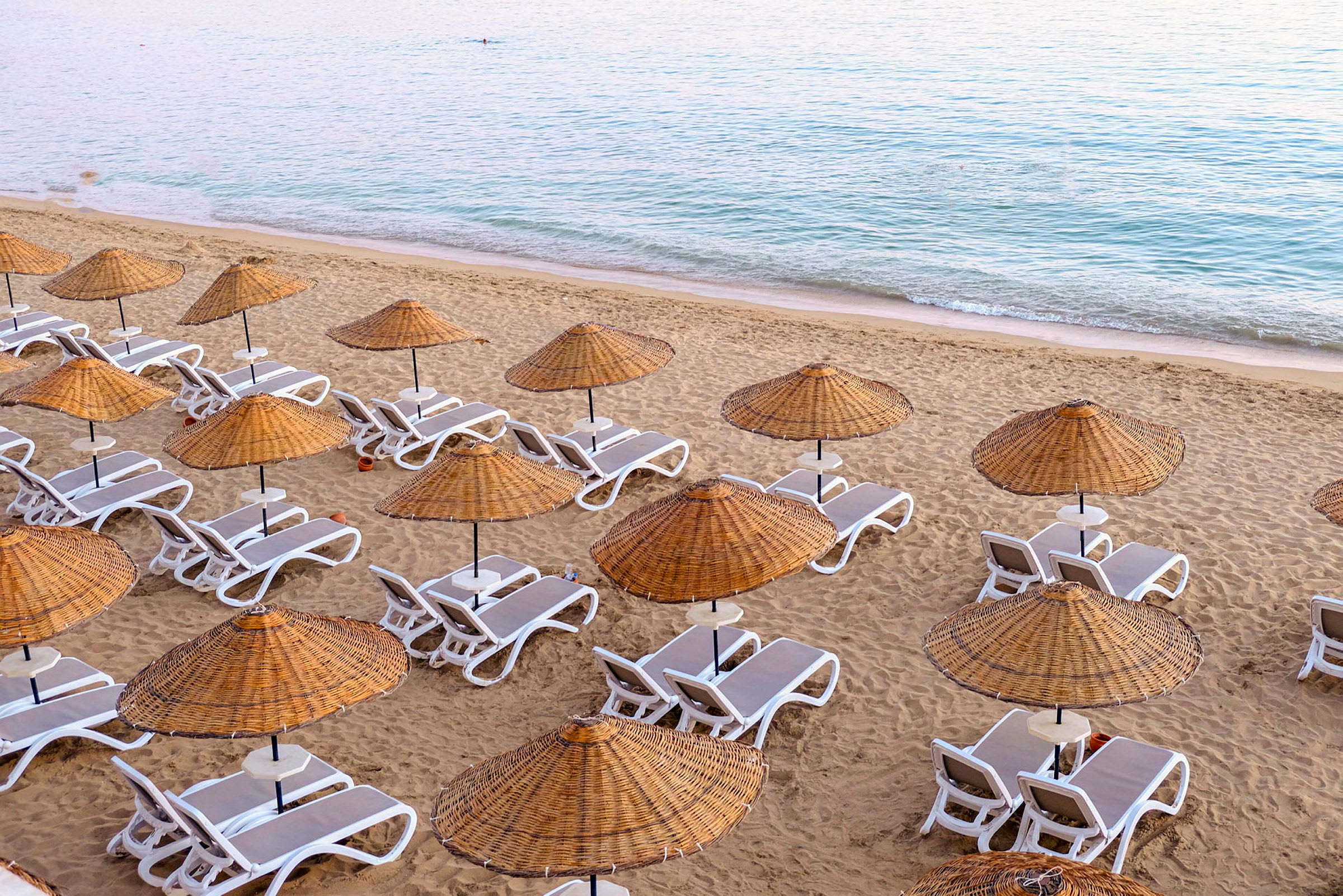 Strand med solstolar och parasoller av rotting. (AI-genererad text)