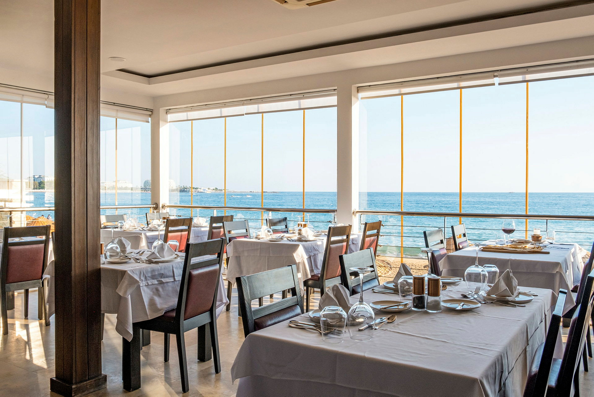 Restaurang med dukade bord och utsikt över havet. (AI-genererad text)