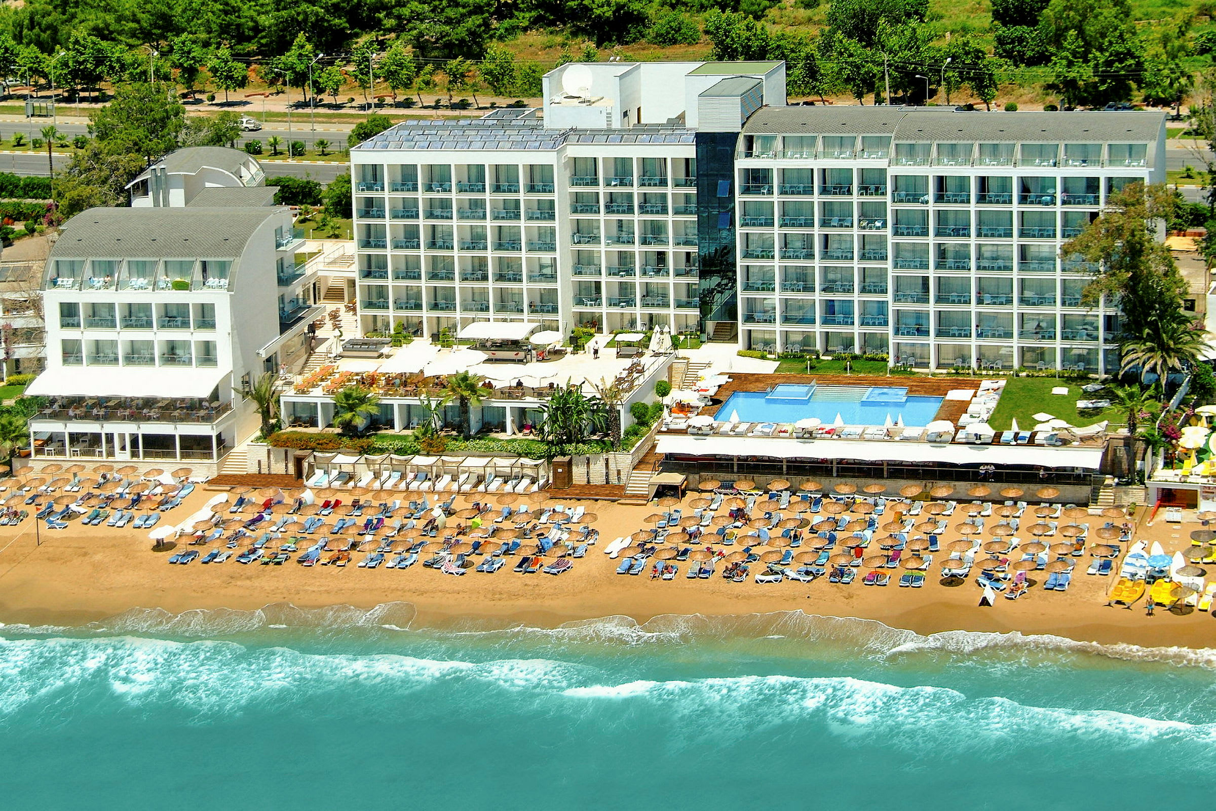 Hotell vid sandstrand med solstolar och parasoller samt poolområde. (AI-genererad text)
