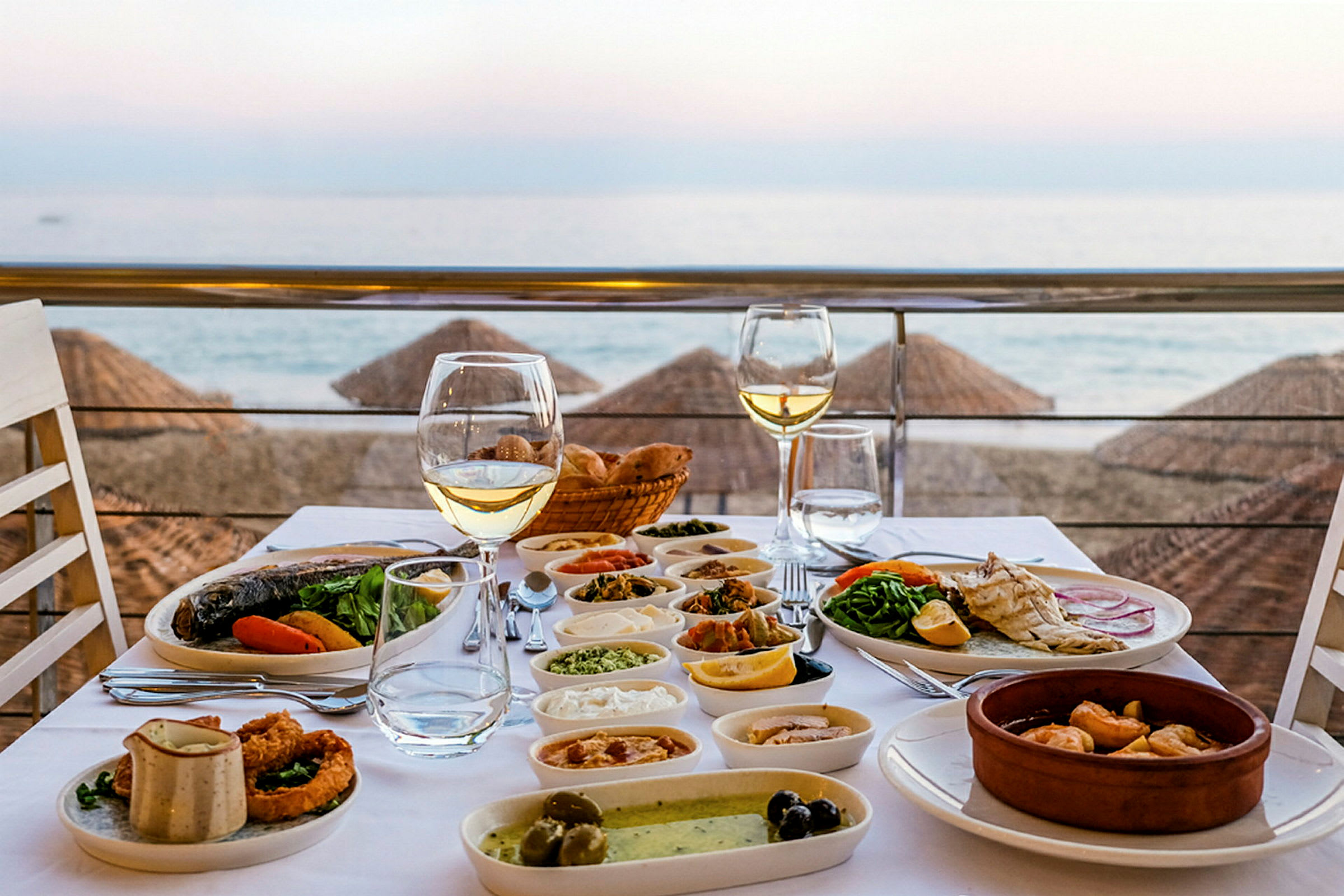 Ett dukat bord med olika maträtter och vinglas, med utsikt över stranden och havet. (AI-genererad text)
