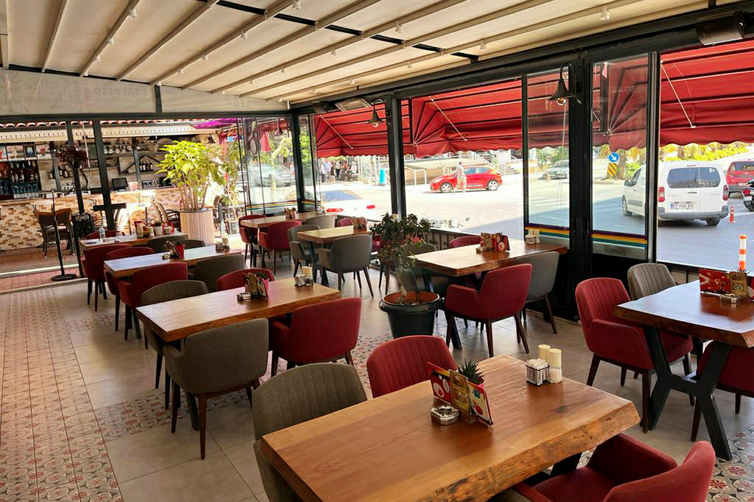 En restaurang med bord och stolar samt stora fönster mot gatan. (AI-genererad text)