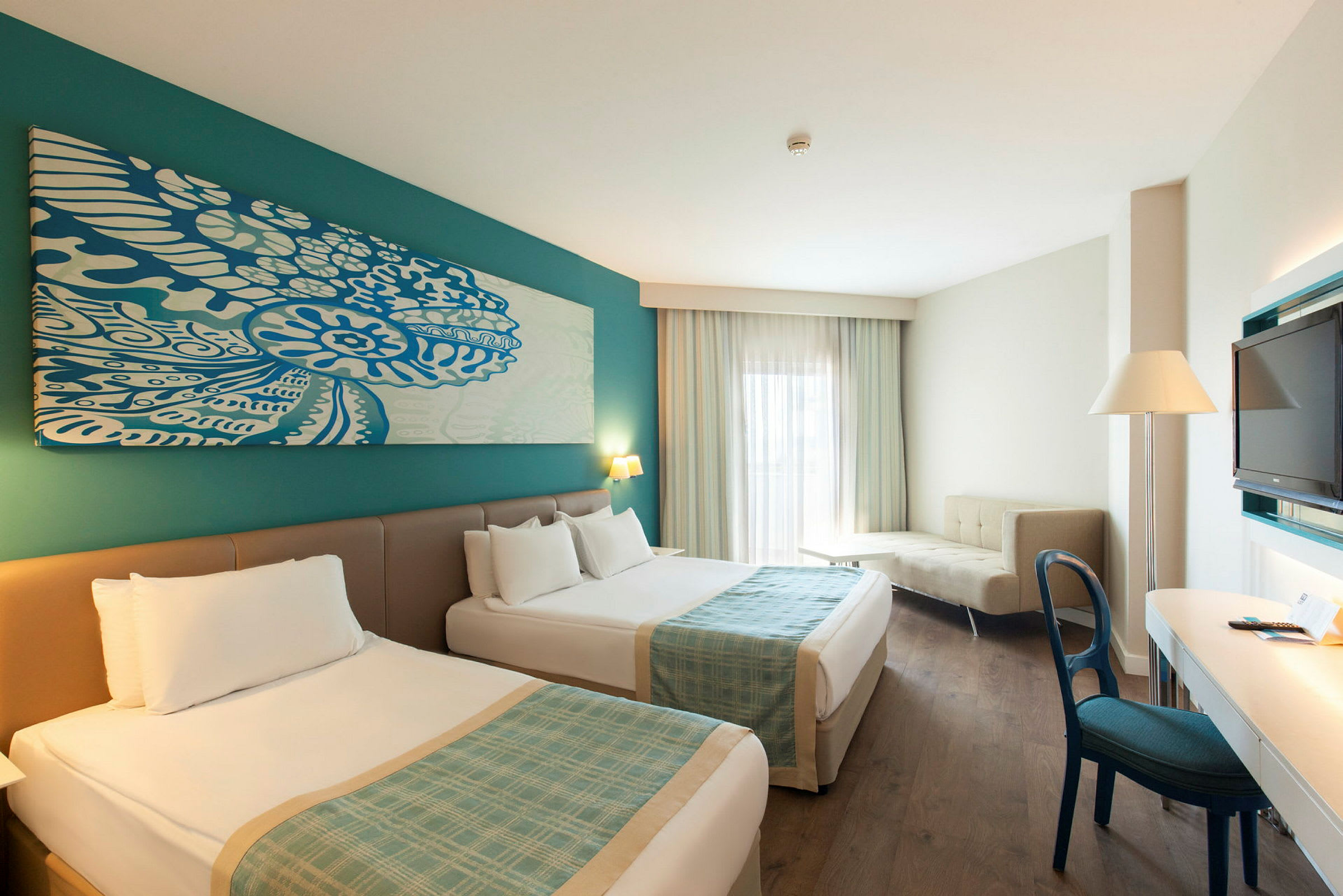 Hotellrum med två sängar, skrivbord, soffa och TV. (AI-genererad text)