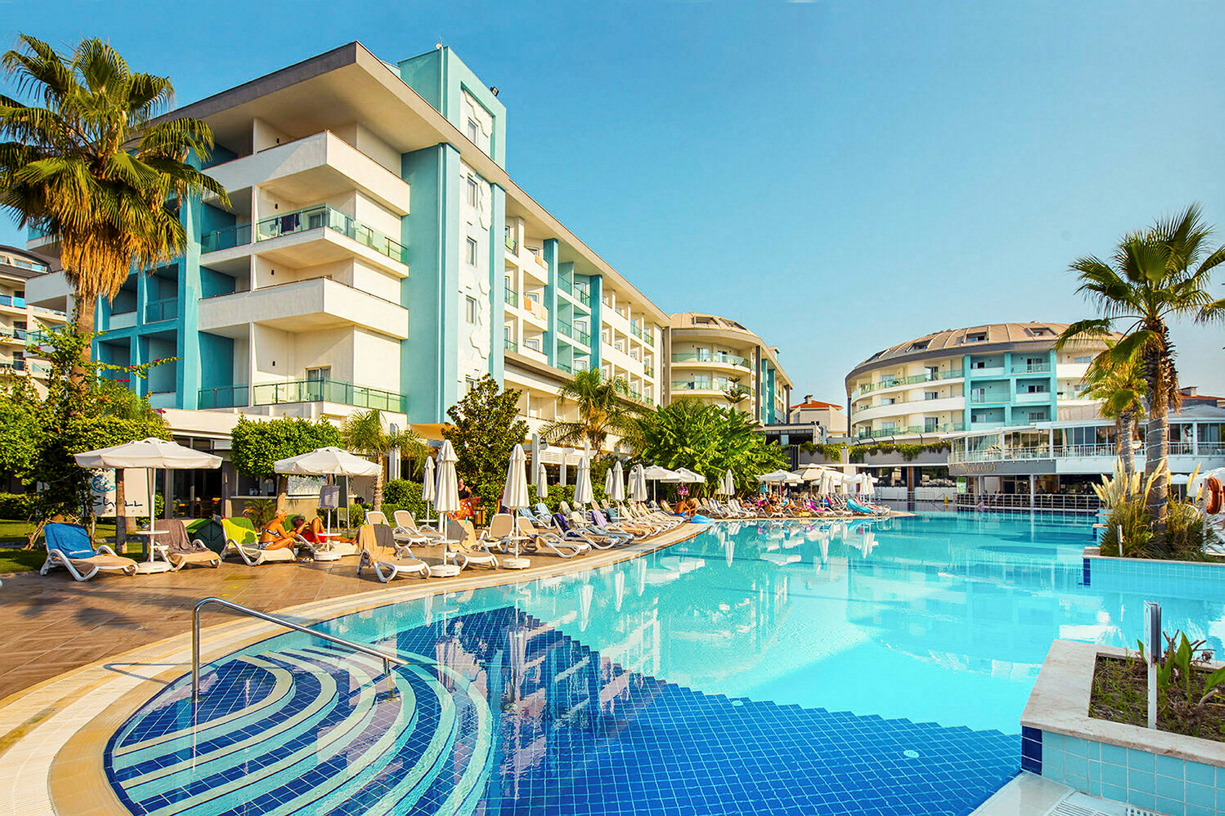 Hotell byggt runt en utomhuspool med solsängar och parasoller. (AI-genererad text)