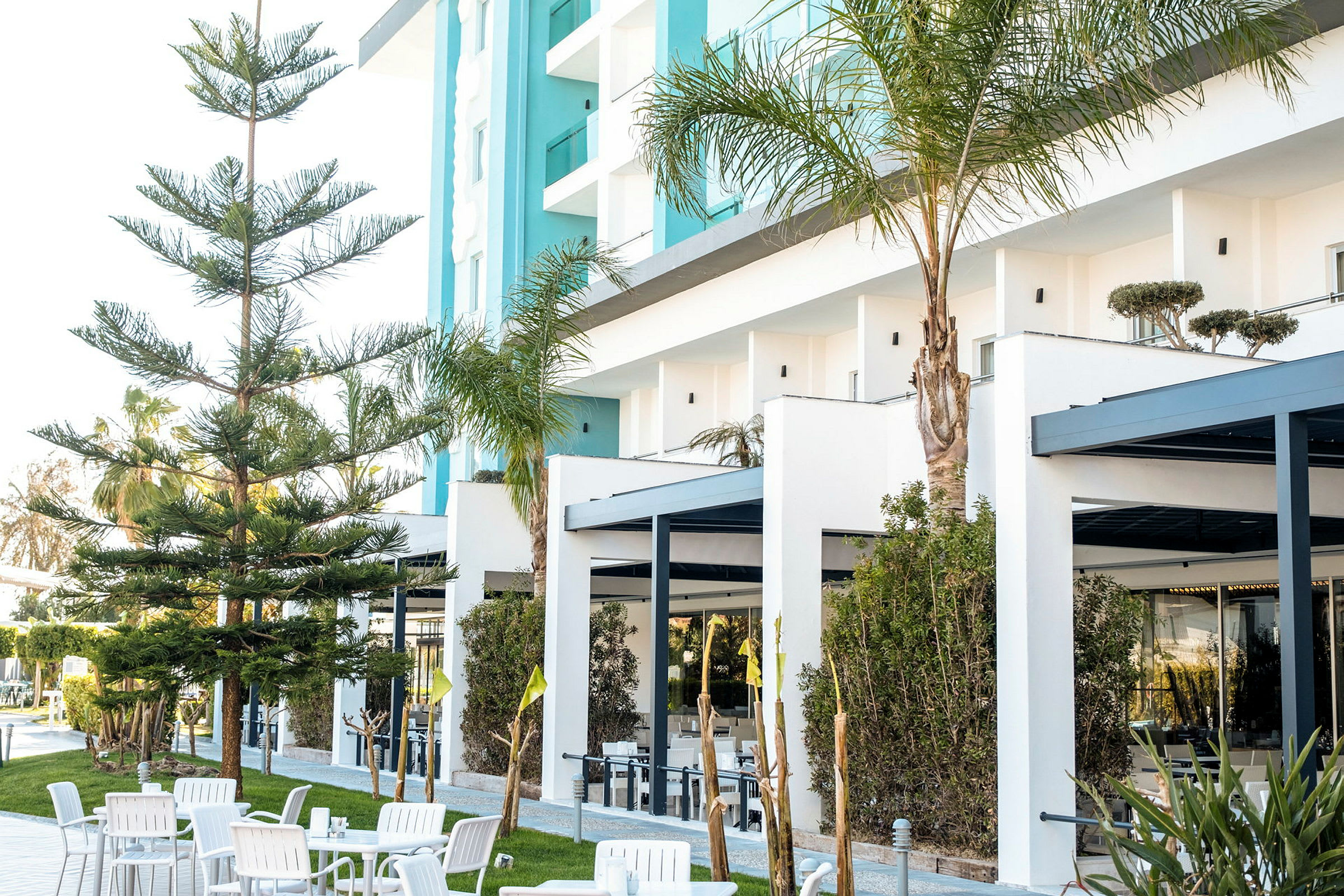 Exteriör av ett hotell med moderna byggnader, träd och sittgrupp. (AI-genererad text)